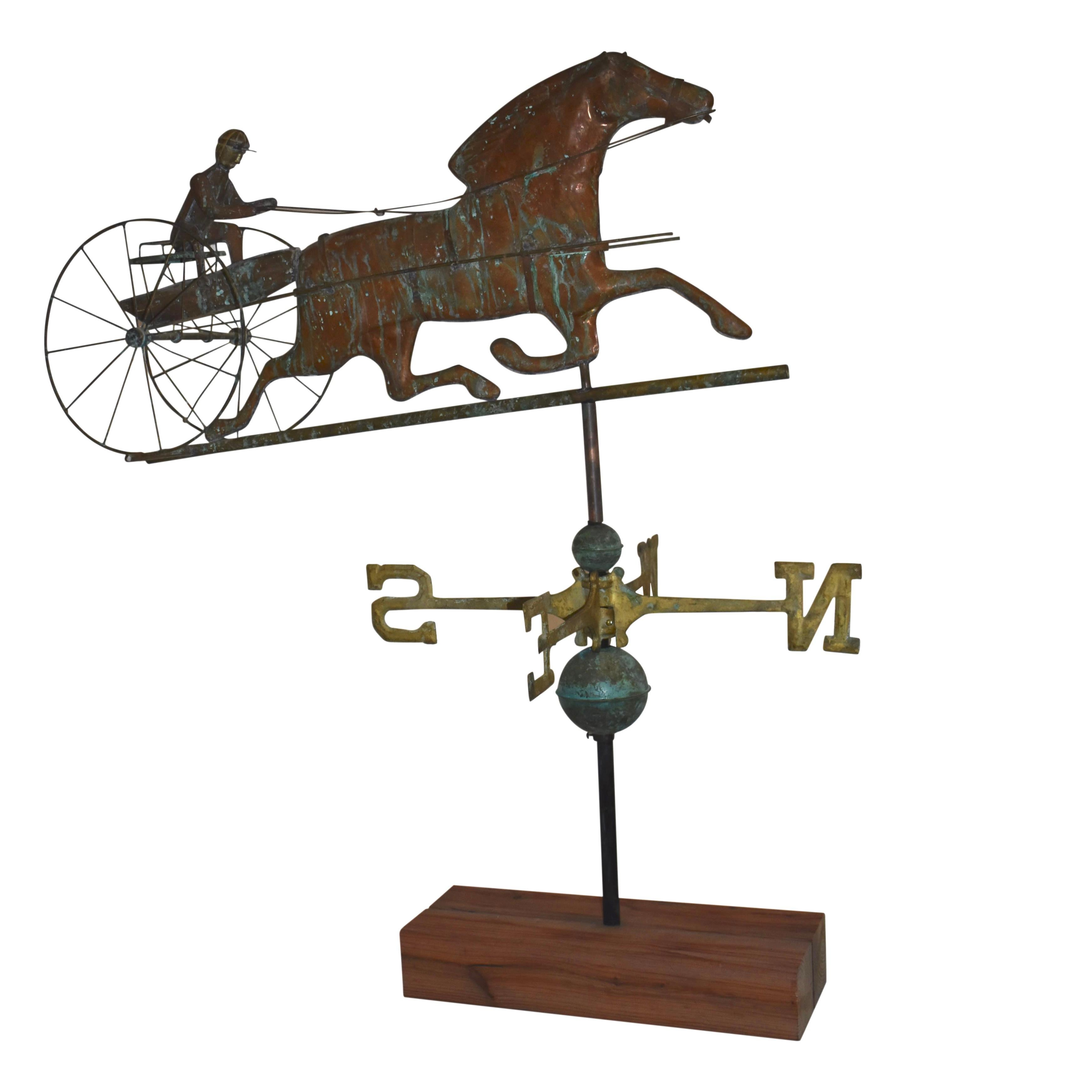 Crafted from copper and brass with verdigris from exposure to the elements, this weathervane features a horse pulling a gentleman in a sulky with classic N, W, S, and E directionals. The dimensions of the figure are 34 x 9.5 x 14.5 inches. Each