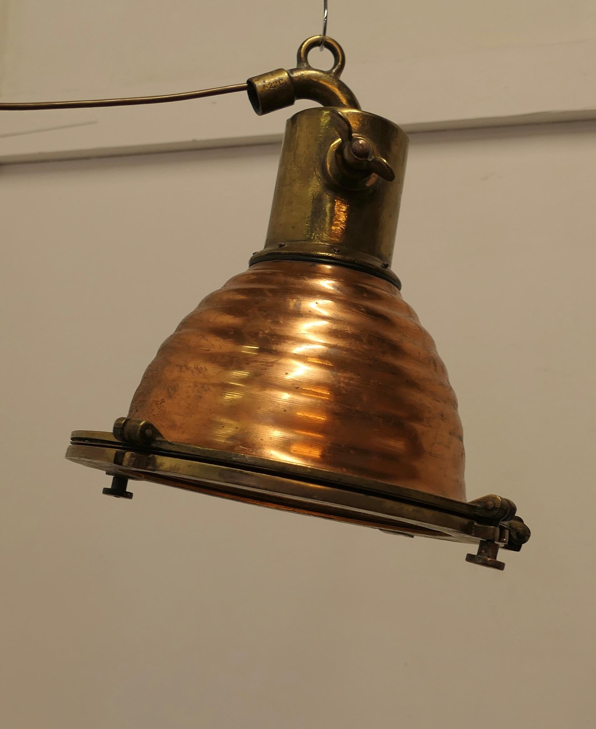 Lampe de recherche ou spot nautique vintage en cuivre et laiton  

La lampe est en cuivre et en laiton. Elle est suspendue par le haut avec une inclinaison de 250 degrés et possède un couvercle en forme de hublot. 
L'intérieur est équipé d'un