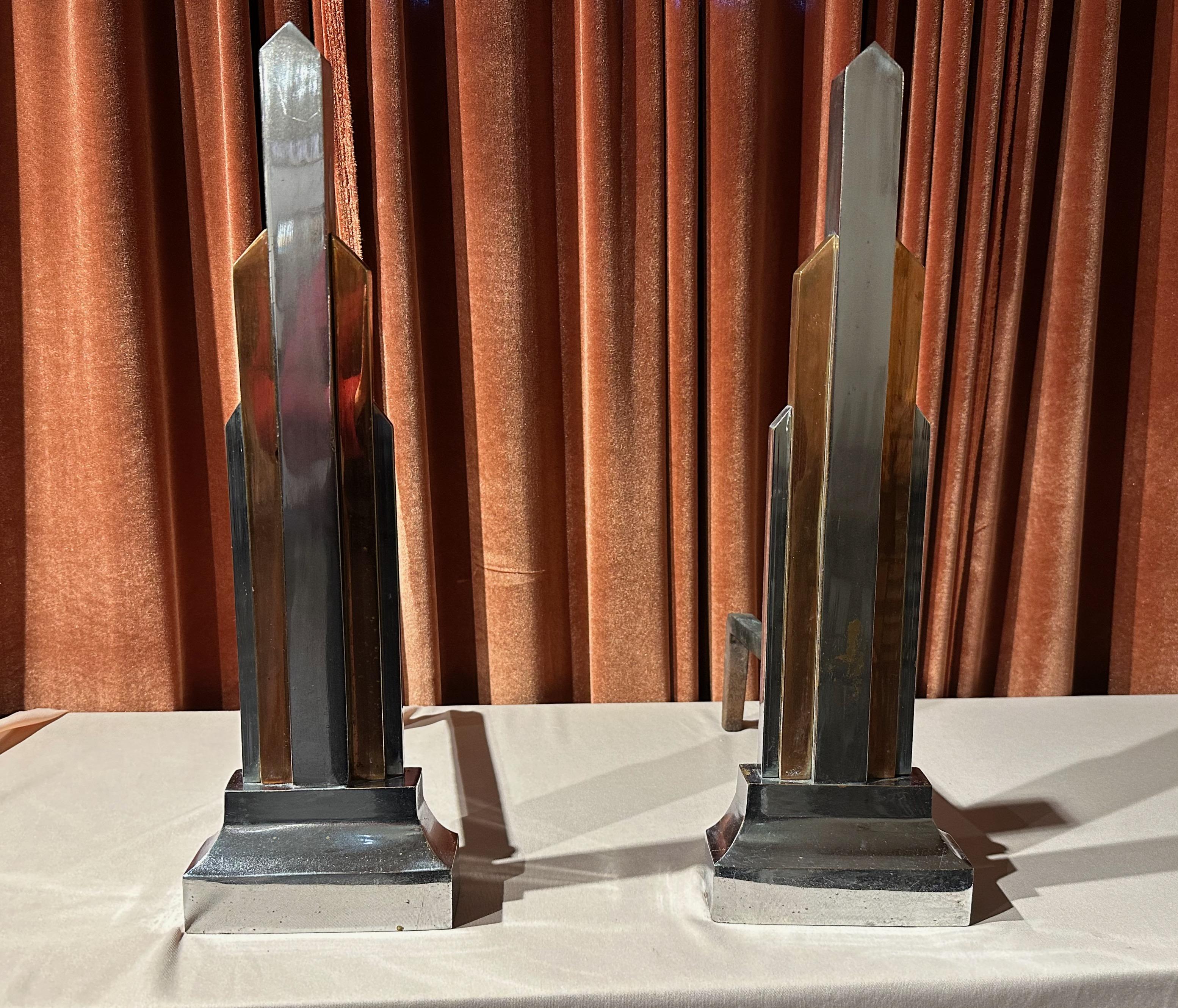 An Art Deco Pair of “Skyscraper” Andirons designed by Donald Deskey, famed designer of Radio City Music Hall as well as hundreds of furnishings,household decorative objects and graphics. These chrome and copper andirons are especially rare as most