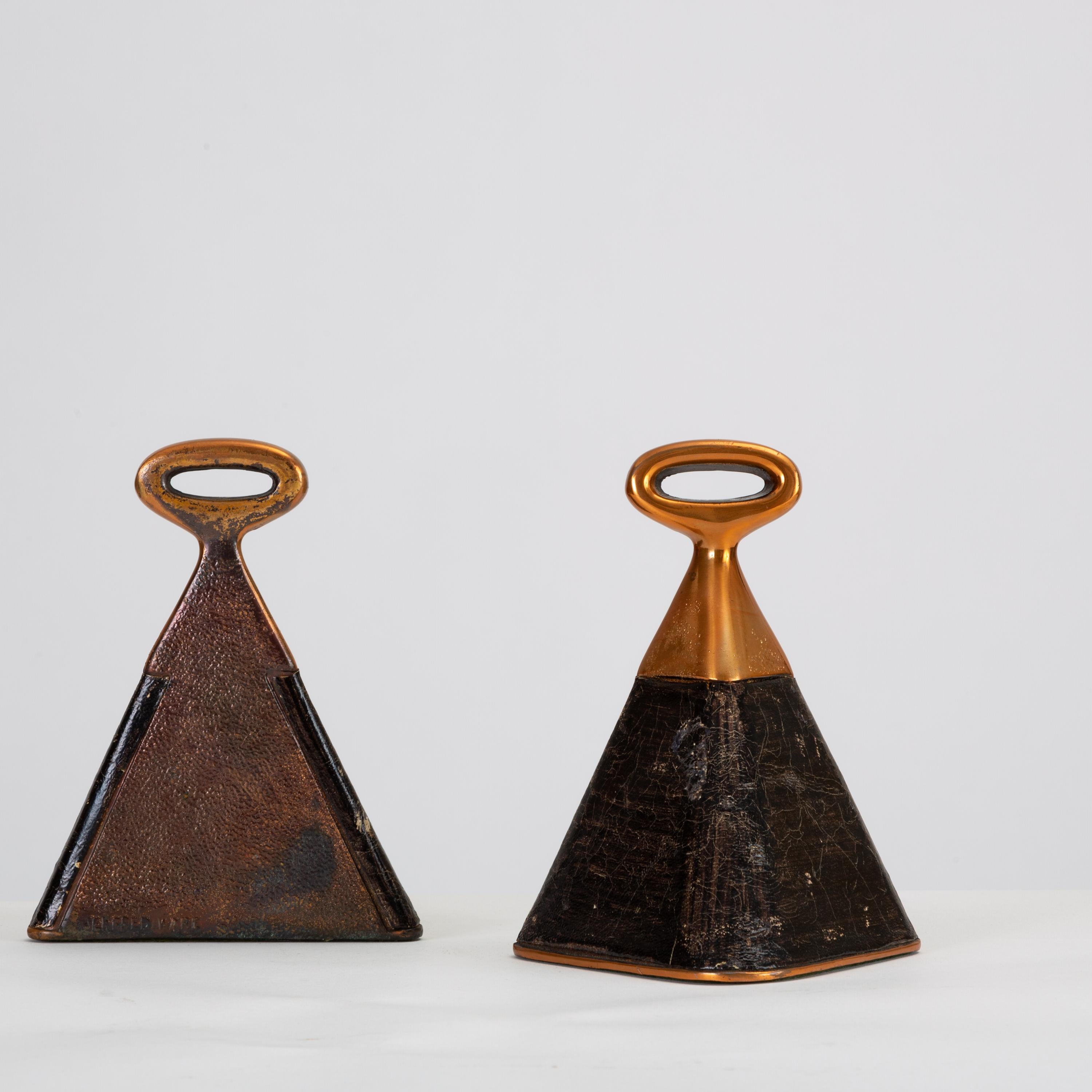 From the popular Jenfred-Ware line, designed by Ben Seibel in 1948 and retailed by Raymor, a pair of copper-plated, cowbell-shaped bookends, wrapped in beautifully aged black leather. The bottom of each bookend is covered in felt to protect