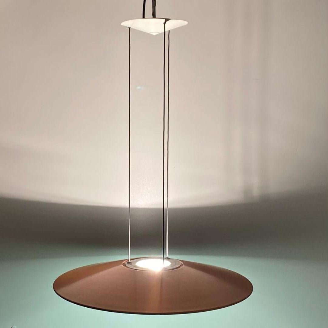 Italian Modern ufo shaped pendant manufactured by Foscarini, Italy in the 1980 's.

Copper and glazed iron disk with double light system supported by three wires attached to an upper small disk. 

Beautiful lighting effect thanks two distinct lights