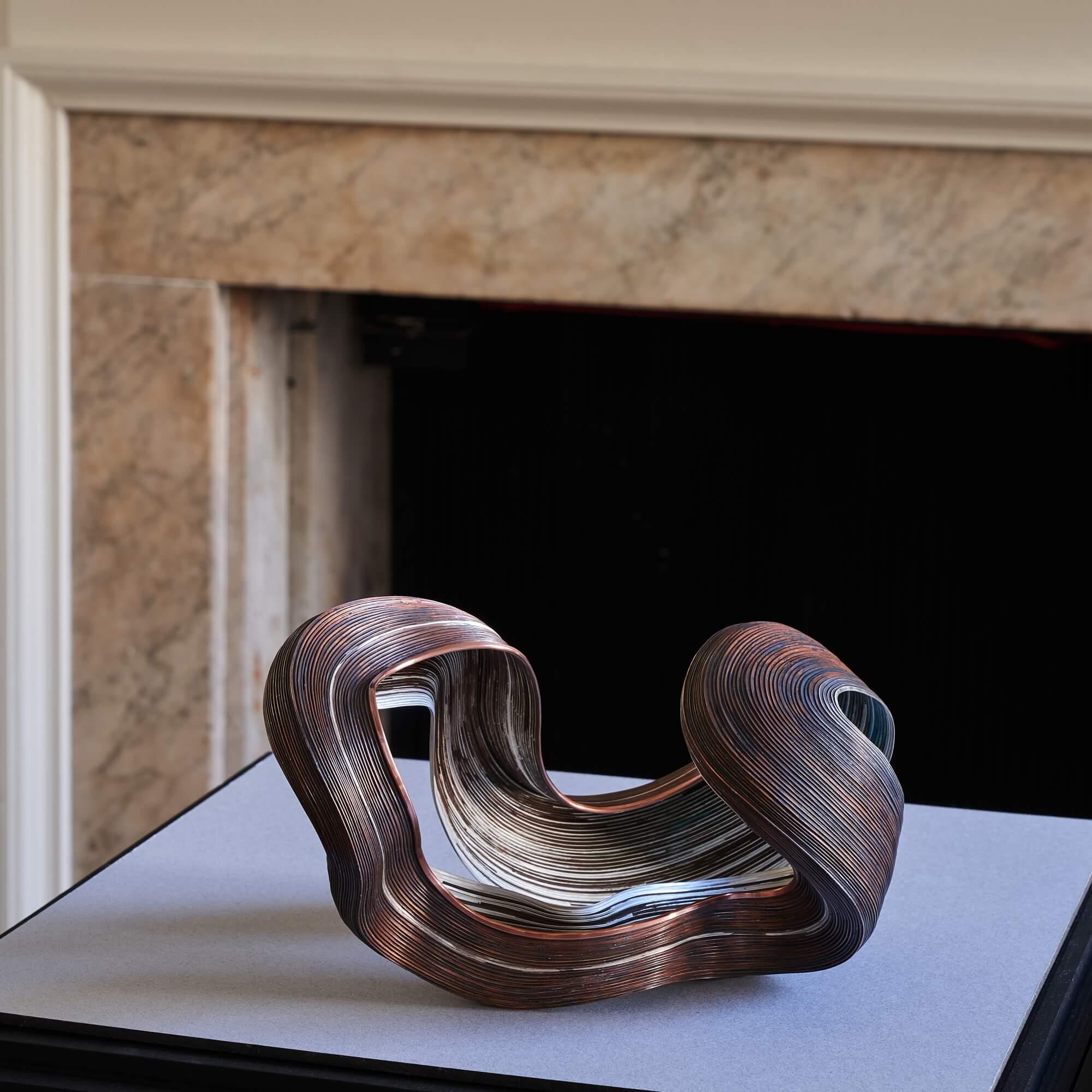 Inspired by the organic nature of her materials, Nan Nan Liu’s earthy copper and sterling silver sculpture is handcrafted using hammering and soldering techniques. Liu initially conceives her abstract forms by working from photographs, building her