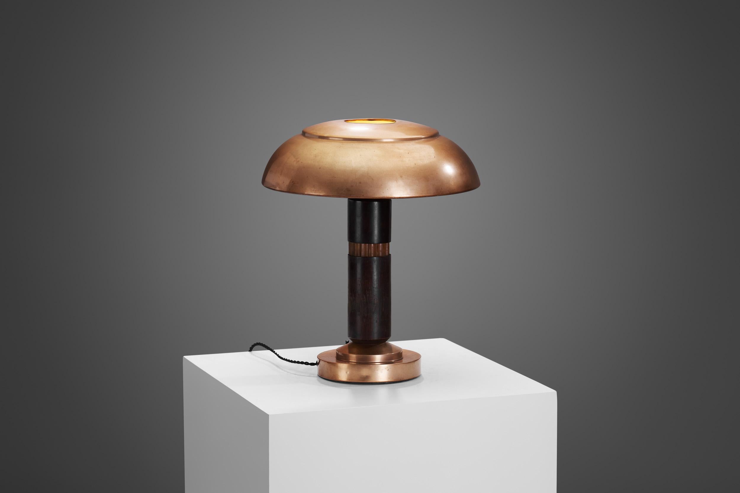 The European Art Deco movement of the 1930s was a beacon of innovation and style, and one of its timeless creations was this copper and wood table lamp. This exquisite piece of functional art epitomizes the elegance and sophistication that