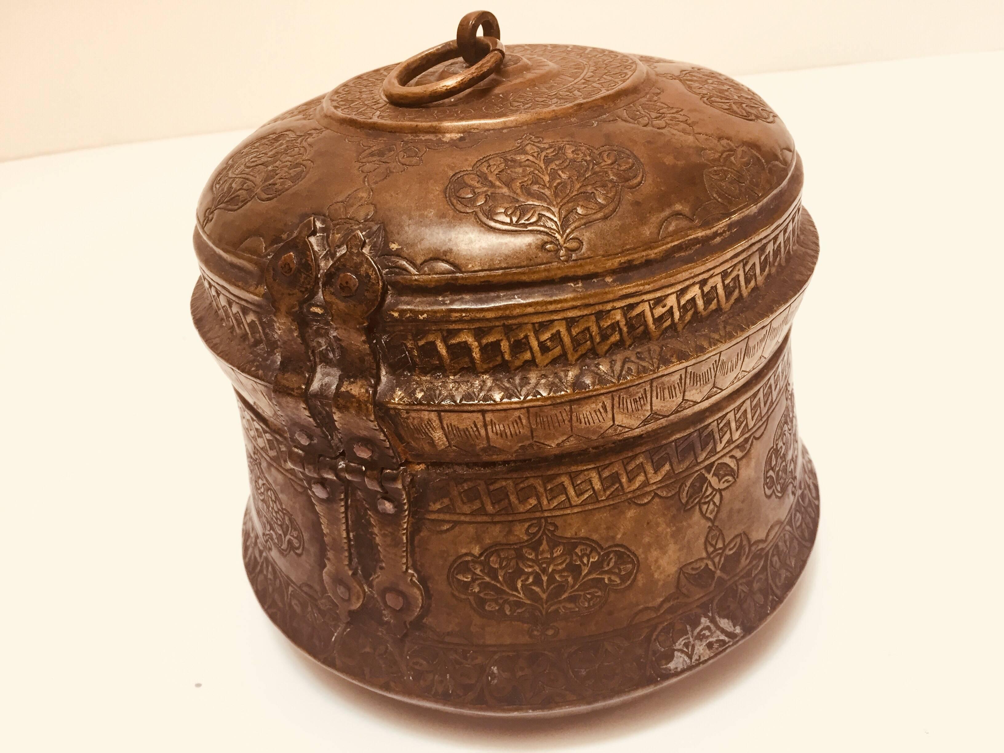 Beautiful handcrafted decorative Indo-Islamic collectible round copper betel nut trinket box with lid, latch and handle.
Delicately and intricately hand-hammered with floral and geometric designs.
Large round metal box hand made in the traditional