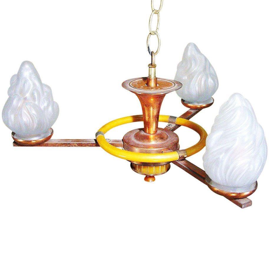 Lampadario in rame a tre bracci con luci in vetro smerigliato a torcia. Il lampadario presenta eleganti accenti circolari in bachelite.