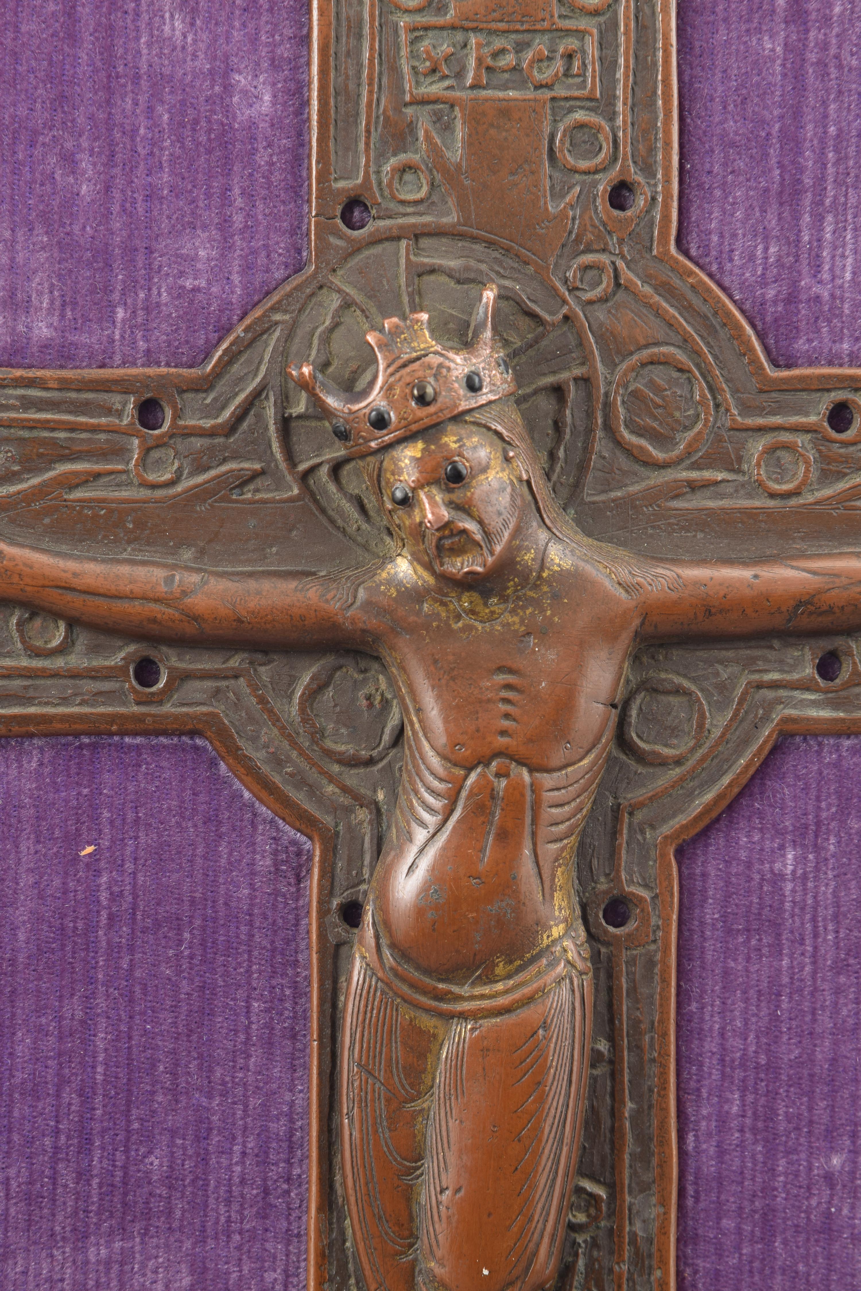 La pièce en cuivre est placée dans un présentoir à dos en bois avec un revêtement en textile. La croix latine présente un élargissement circulaire dans l'union des barres transversales et en elle est placé un Christ crucifié avec quatre clous,