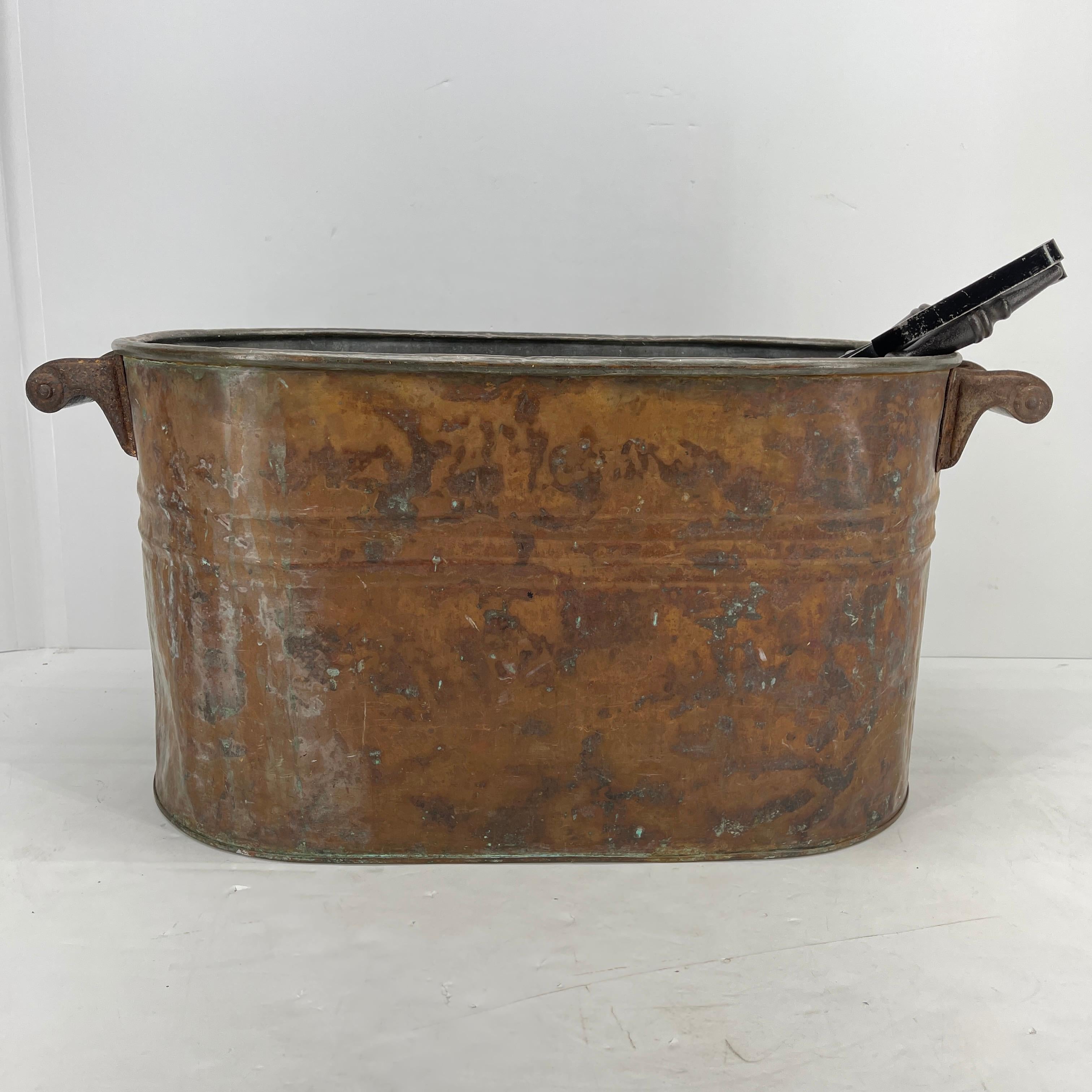 19th century French Napoleon copper bucket log holder with wooden handles. This large and sturdy log holder is grand in it's presentation and is in good condition; without holes and handles in tact, it can hold a grand bundle of logs and will look