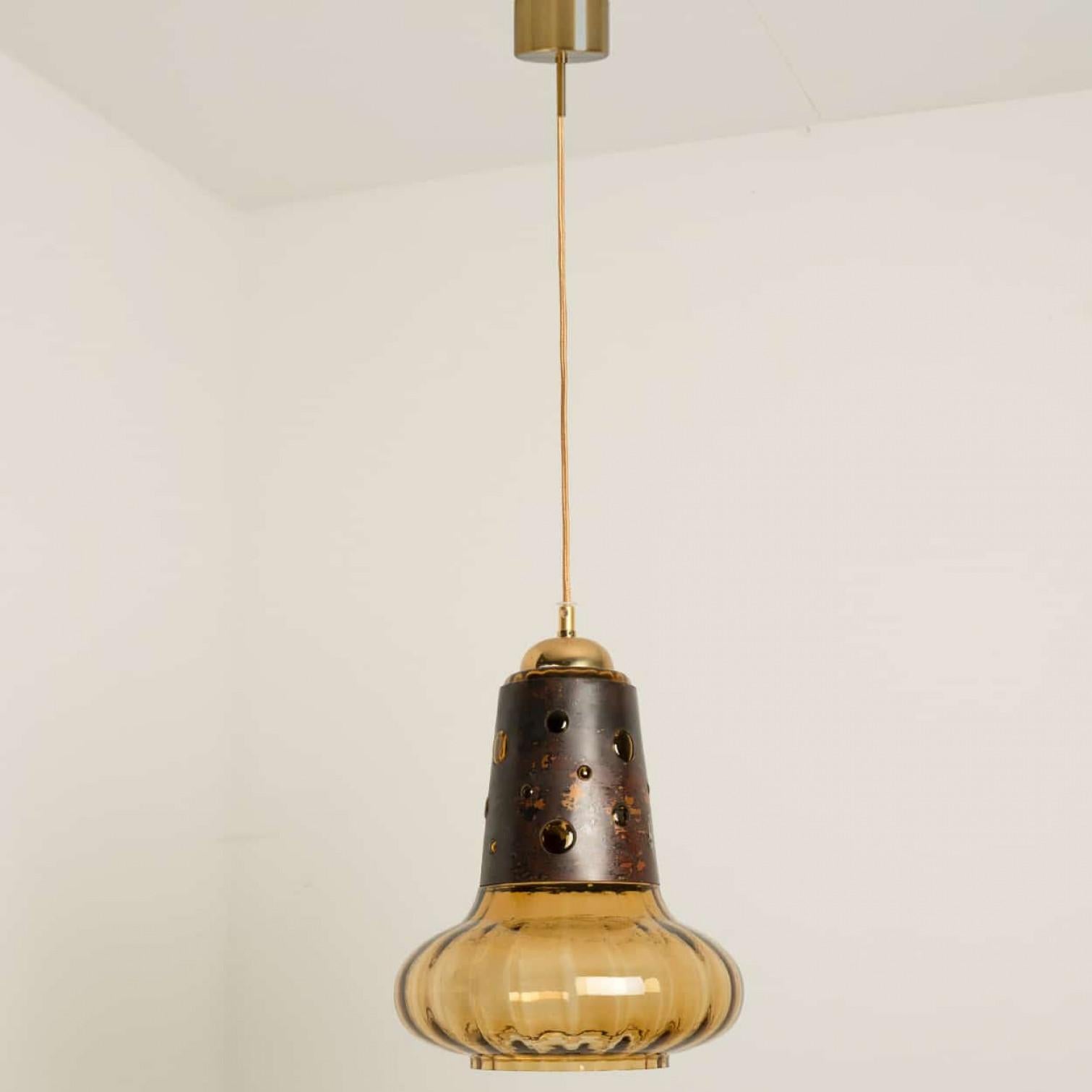 Pendentif brutaliste dans le style de Nanny Still McKinney, Pays-Bas 1960.

Cette suspension en cuivre traité à l'acide avec un abat-jour en verre soufflé rayé ambre crée une illumination étonnante. Une véritable pièce maîtresse.

Nettoyé, bien