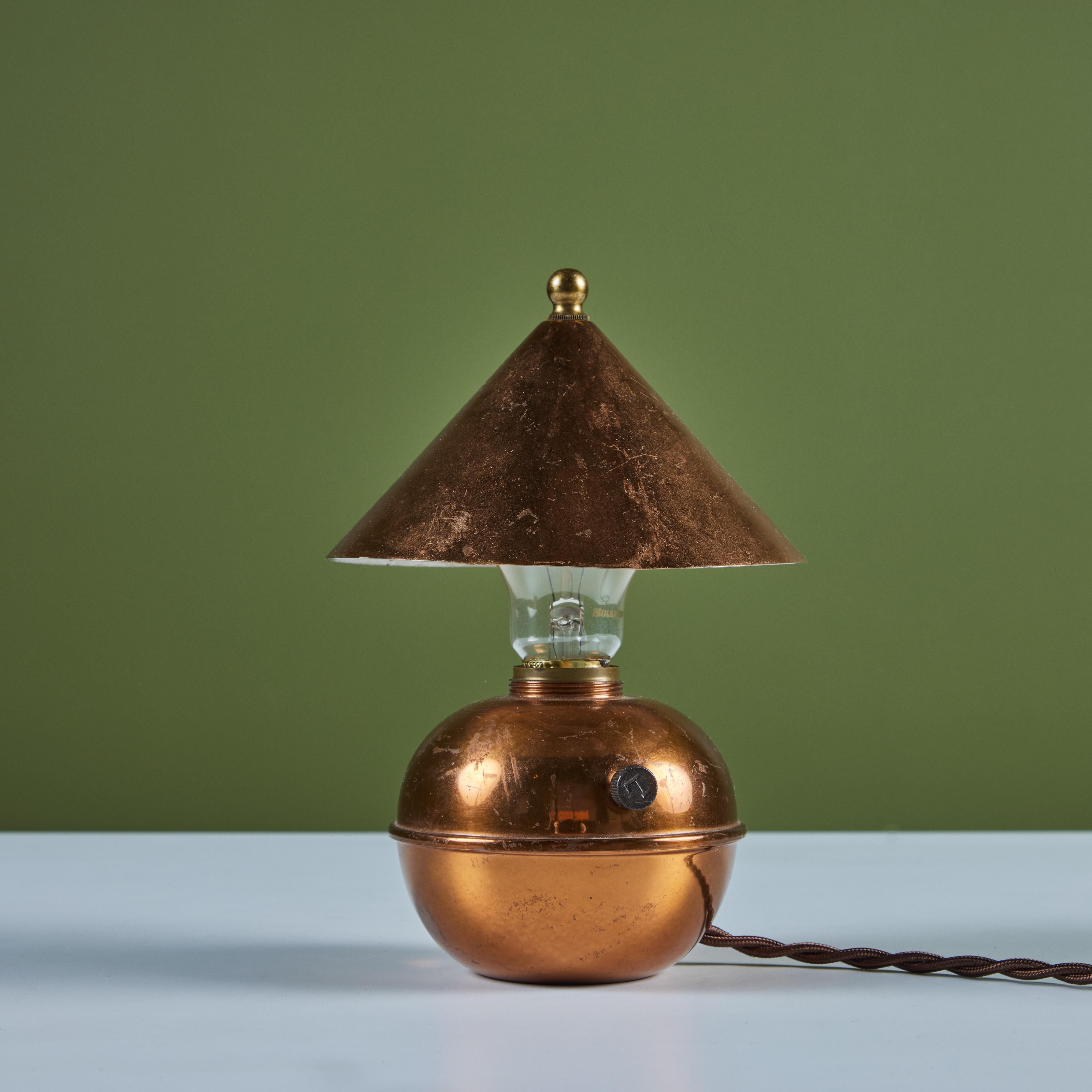 Petite copper table lamp by Ruth Gerth for Chase, c.1930s, USA. The Art Deco lamp features a cone shaped shade and bulb body in patinated copper. The minimalist design is playful and a fun piece to add to a shelf or desk.  Impressed with [Chase] and