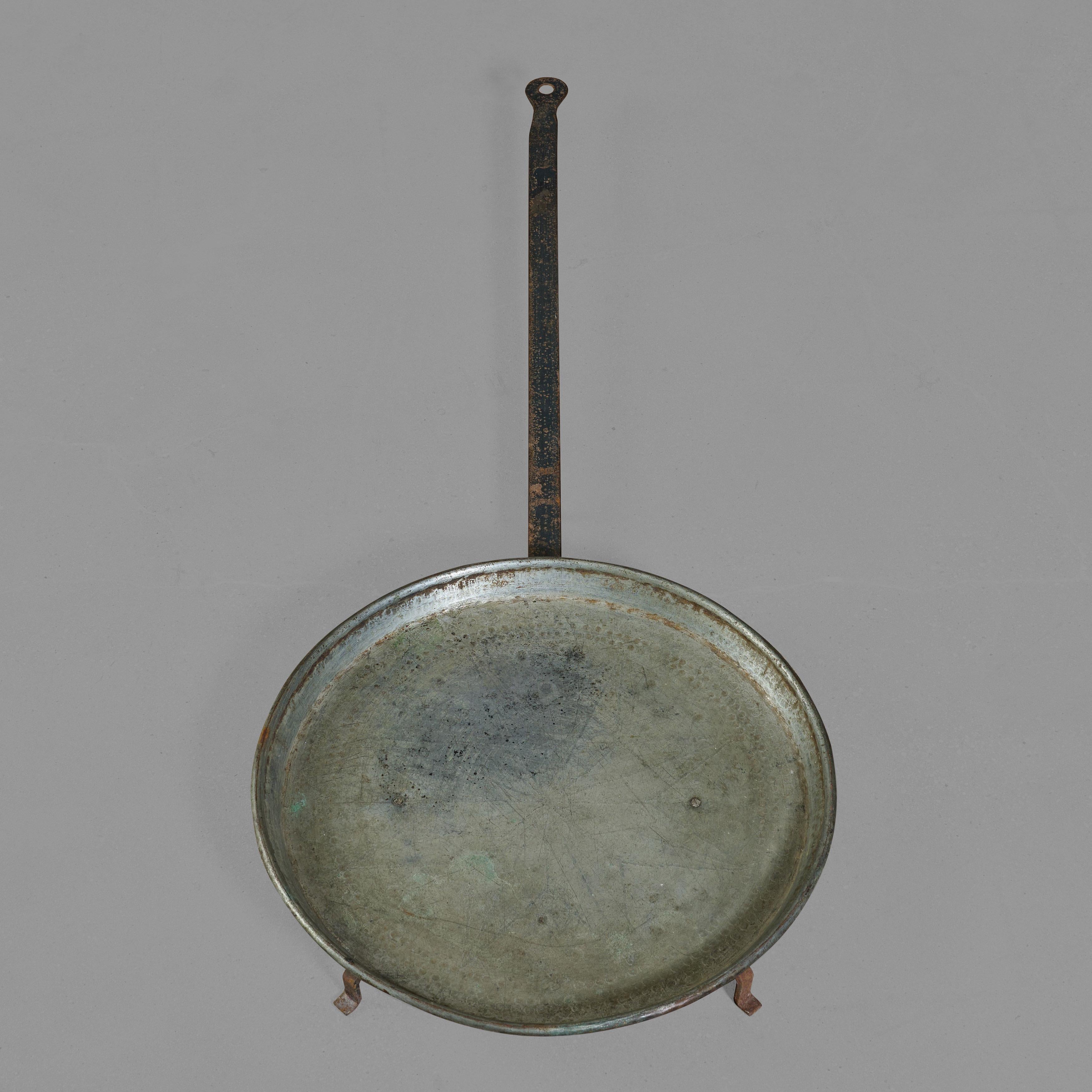 Paellapfanne aus Kupfer und Eisen mit dekorativer Schale und großem Griff.

