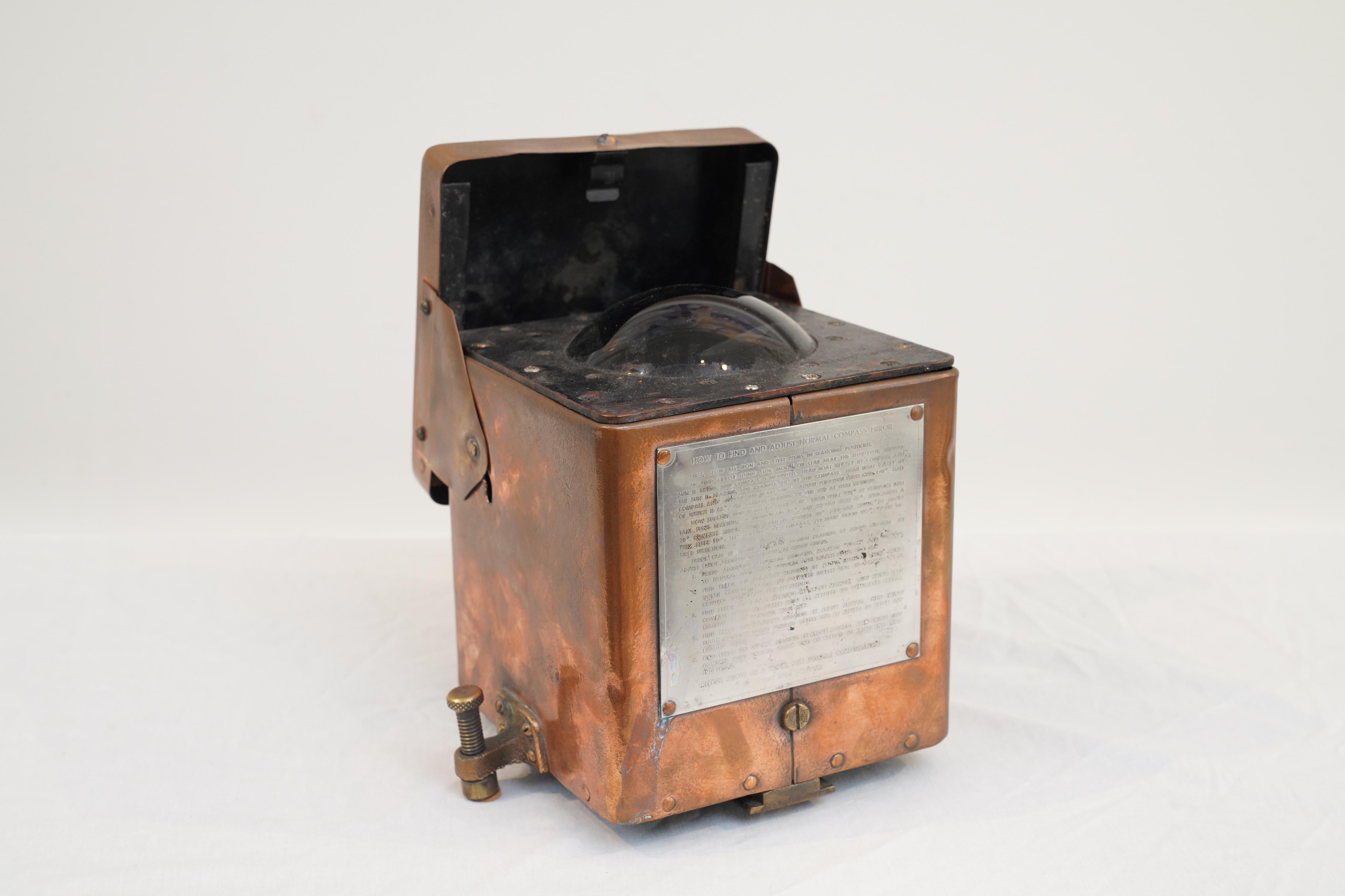 An American, copper, liquid compass from a ship's lifeboat. It has a snap-shut lid to protect it from the elements and the original brass bolts that held into place. The compass sits under a glass dome and is in perfect working order. The steel face