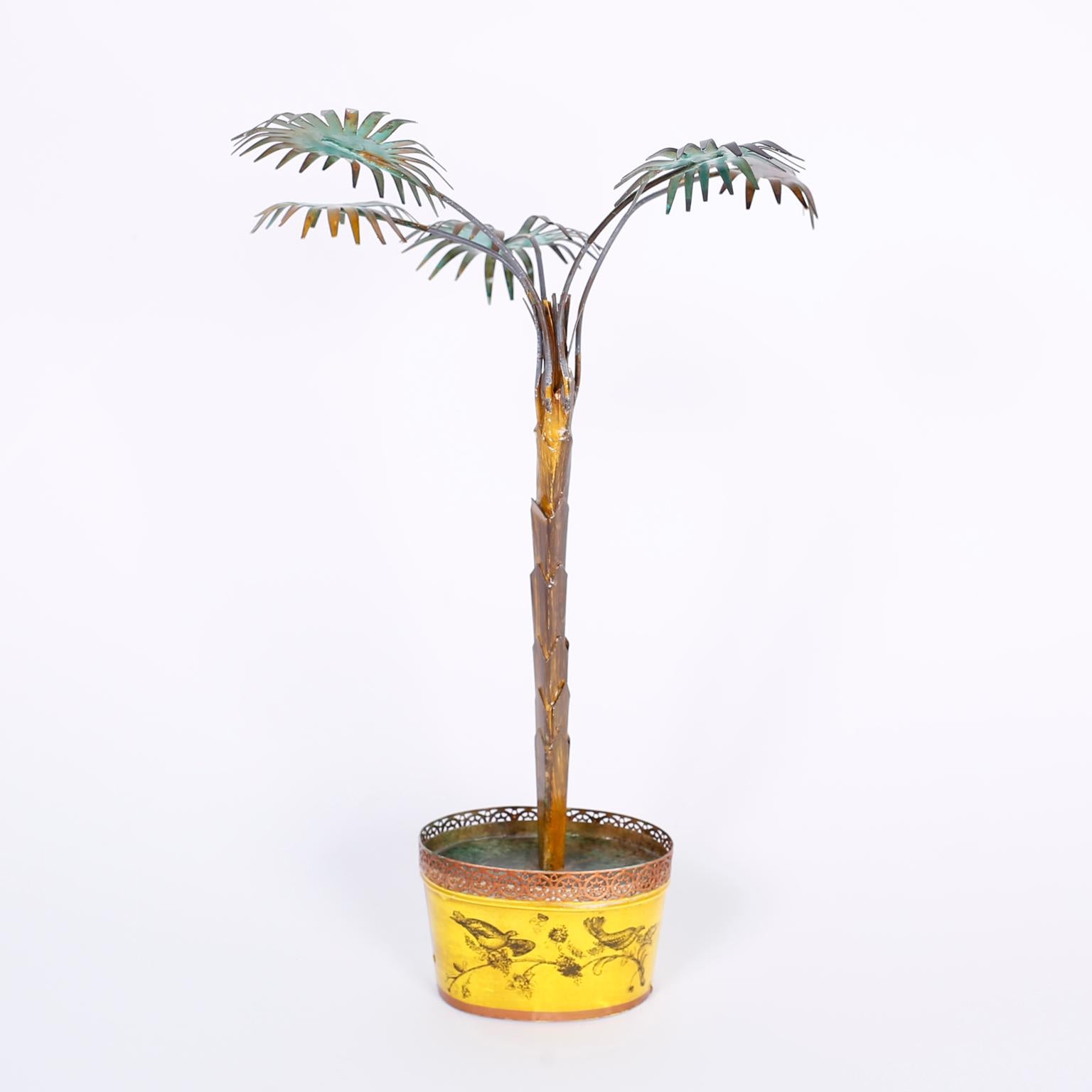 Stylized Italian palm tree with a rustic patina set in a classic yellow tole planter decorated with birds and flowers.