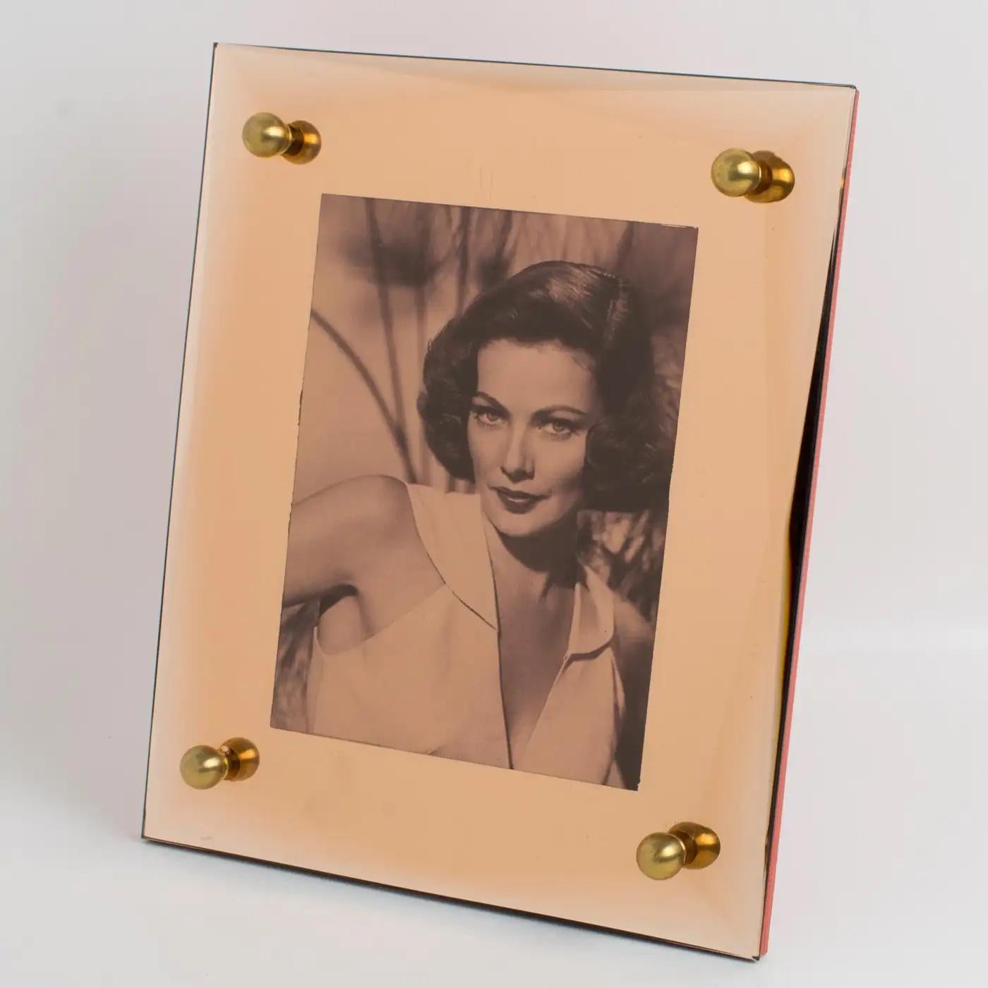 This lovely mirrored glass picture photo frame was produced in France in the 1940s. The mirror has a deep geometric bevelling, and a rare copper or pink-peach color, complimented with gilded brass bead cabochons. The frame can be placed only in a