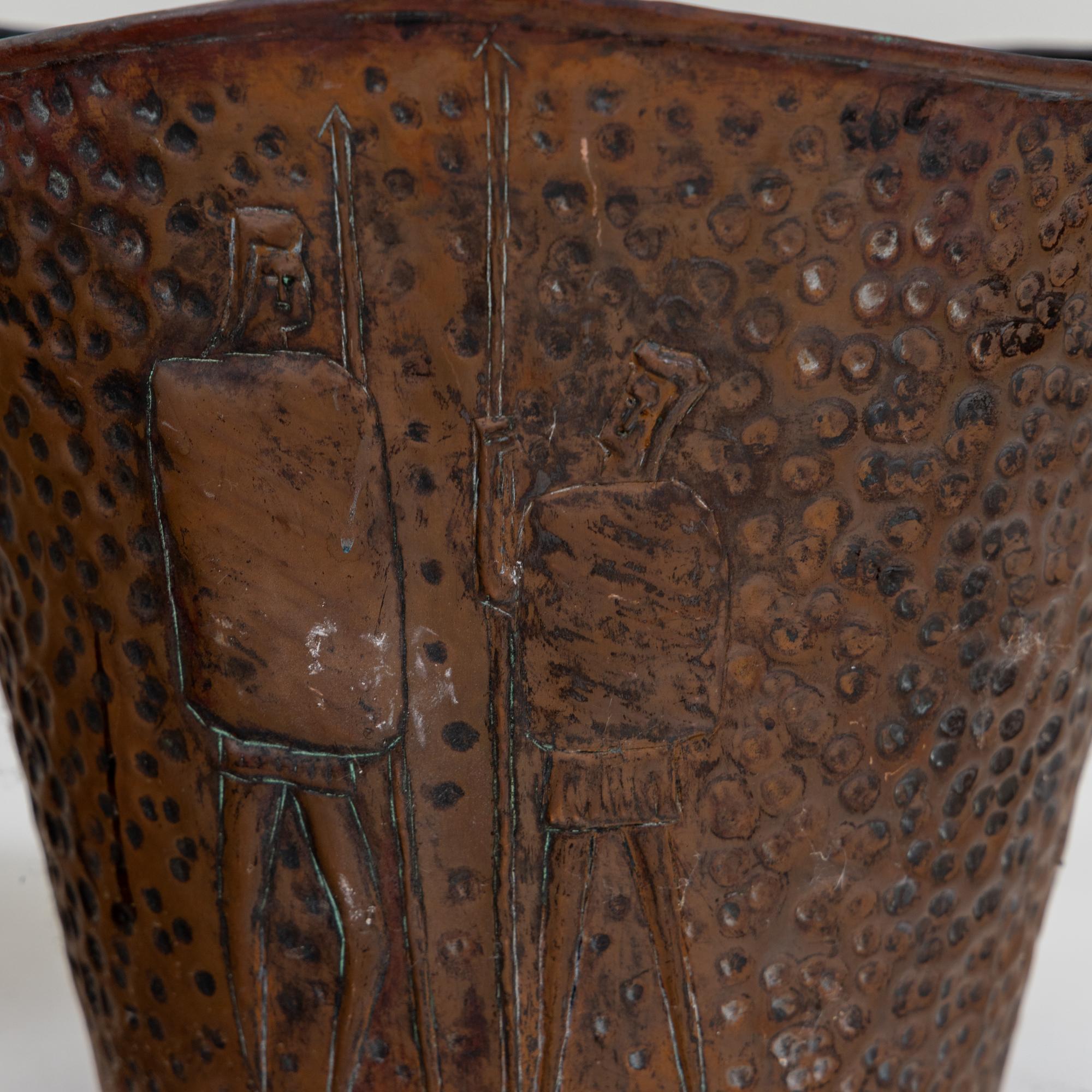 Ein Paar Pflanzentöpfe aus Kupfer mit Reliefwänden und gewelltem Rand. Ein Topf zeigt stilisierte Krieger, der andere Granatäpfel.