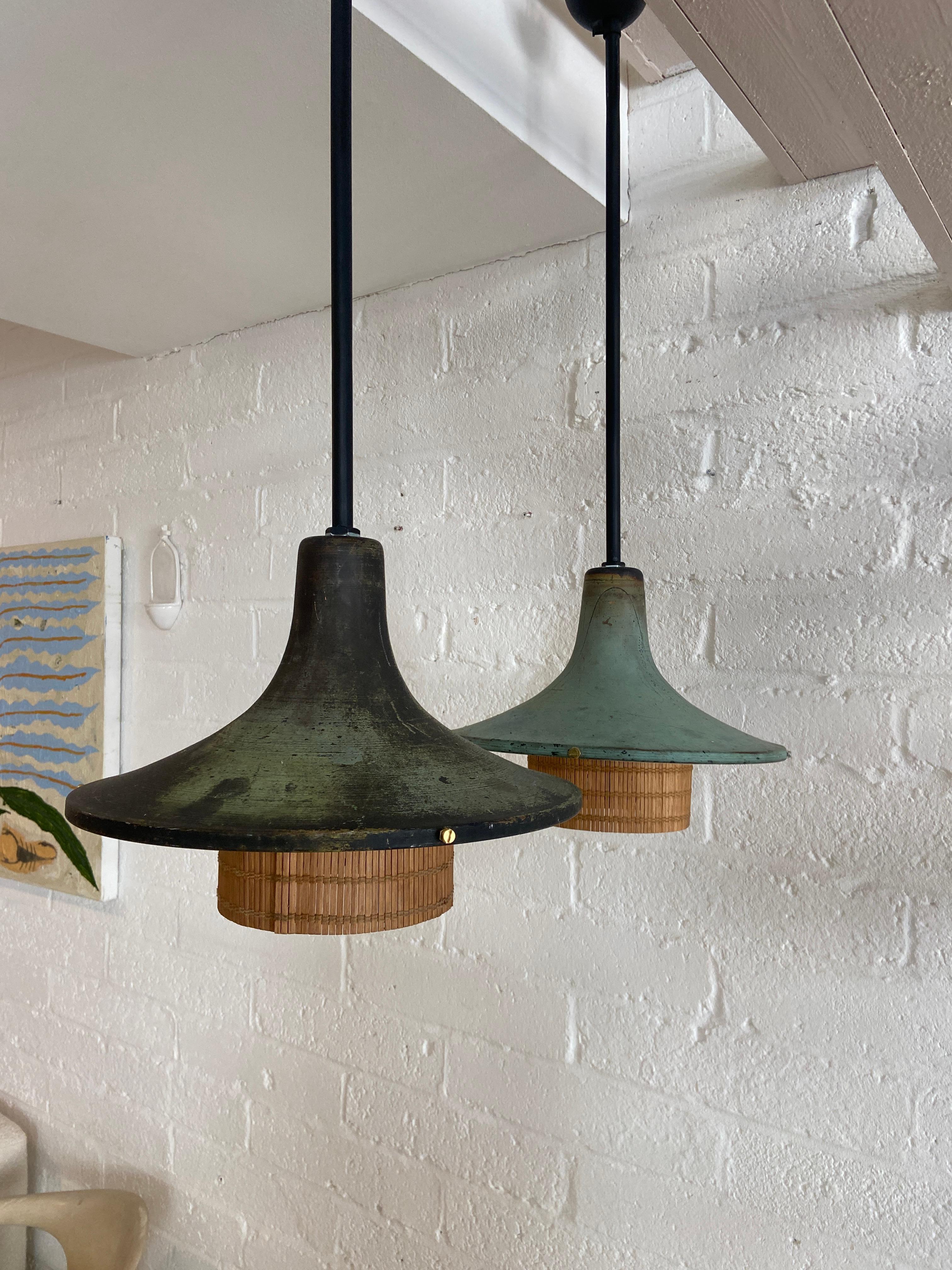 A stunning pair of pendant lights crafted from copper and rattan. Each pendant showcases a unique and captivating verdigris patina, with one displaying a slightly more aged appearance than the other, adding to their character and charm. The