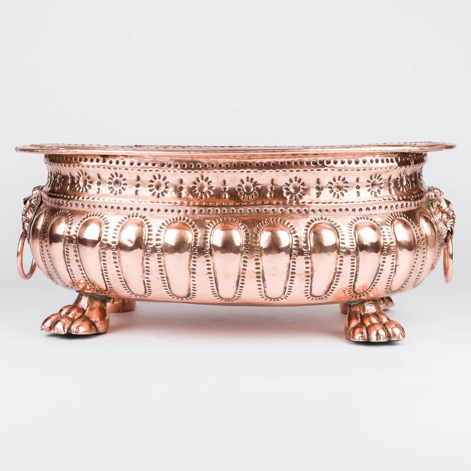 Jardinière en cuivre repoussé avec des poignées en anneau en forme de tête de lion et des pieds en forme de pattes.