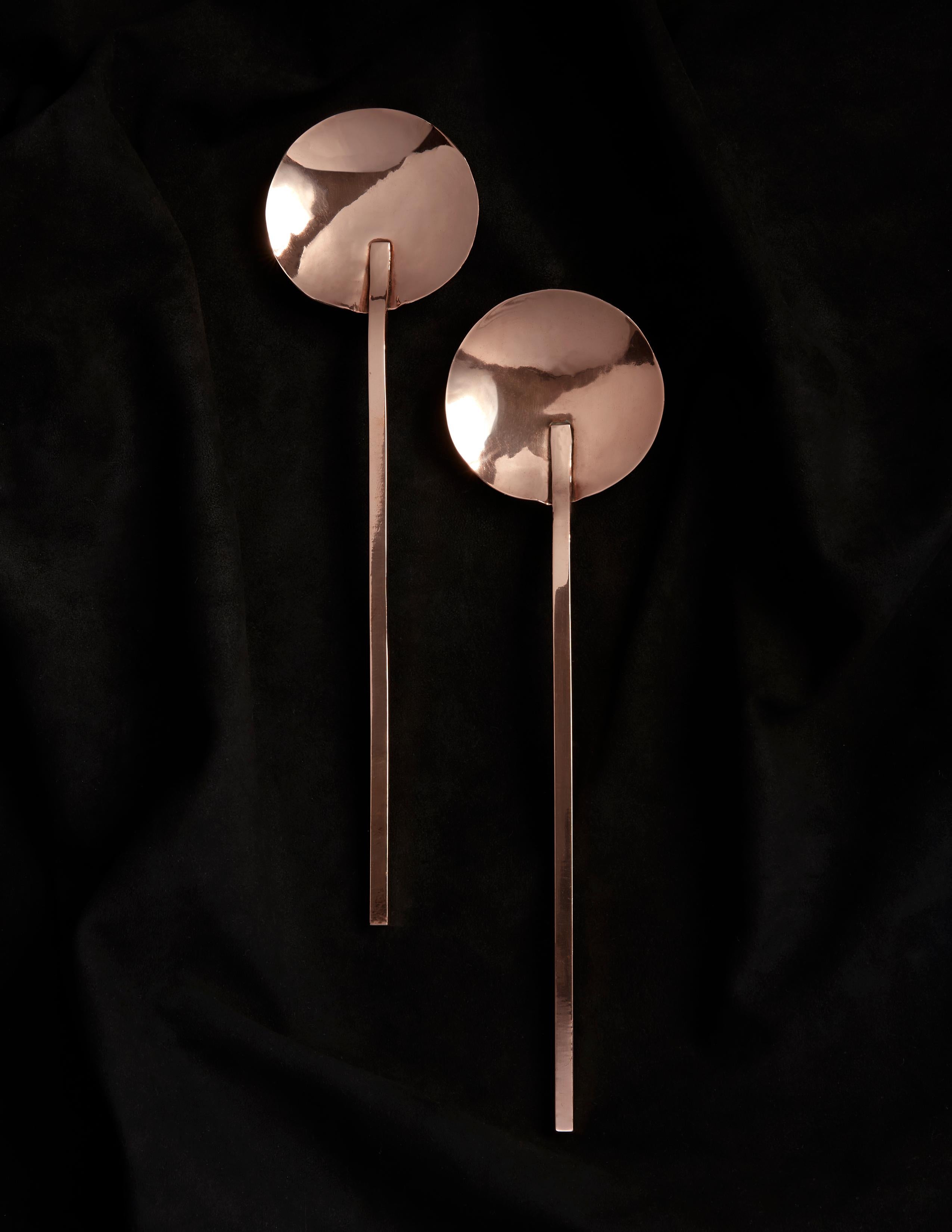Two-piece set of modern high-polished copper serving spoons. Fabricated in rich copper and then finished by hand in his Brooklyn, NY studio, these pieces are the creation of silversmith and jewelry designer Heath Wagoner under HW. Studio. Designed