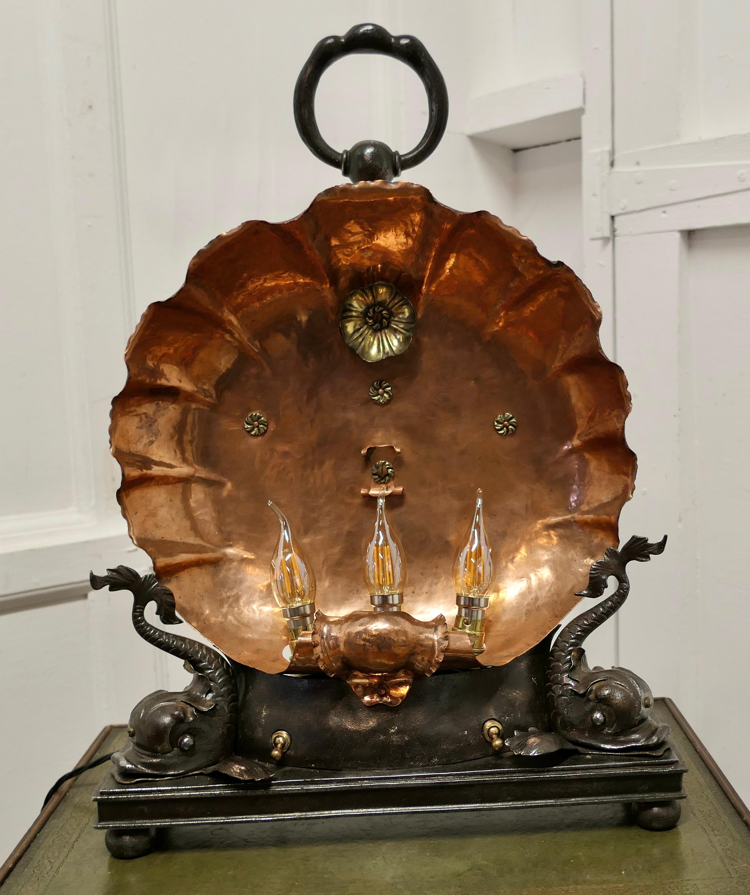 
Copper Scallop Shell with Dolphins,  Electric Table Lamp, 

A magnificent decorative piece, this stunning stand alone lamp has been made from an early 20th Century Electric heating fire
The Copper Scallop shell is set on the original Iron Frame