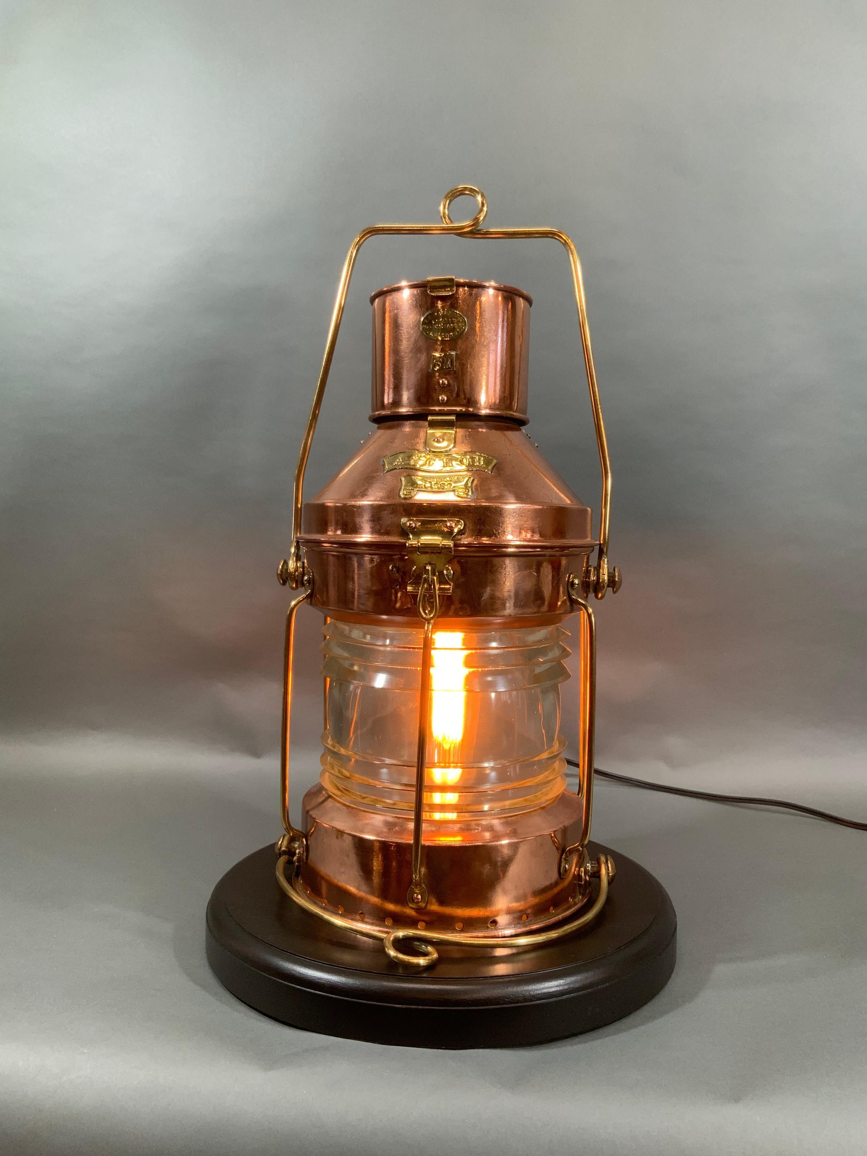 Ship's lantern of copper and brass. Meticulously polished and lacquered. Fitted with a glass Fresnel lens with protective brass bars. Vented top. Hoisting and bale handles. Wired with socket and cord for home use. Makers badge from RC Murray.