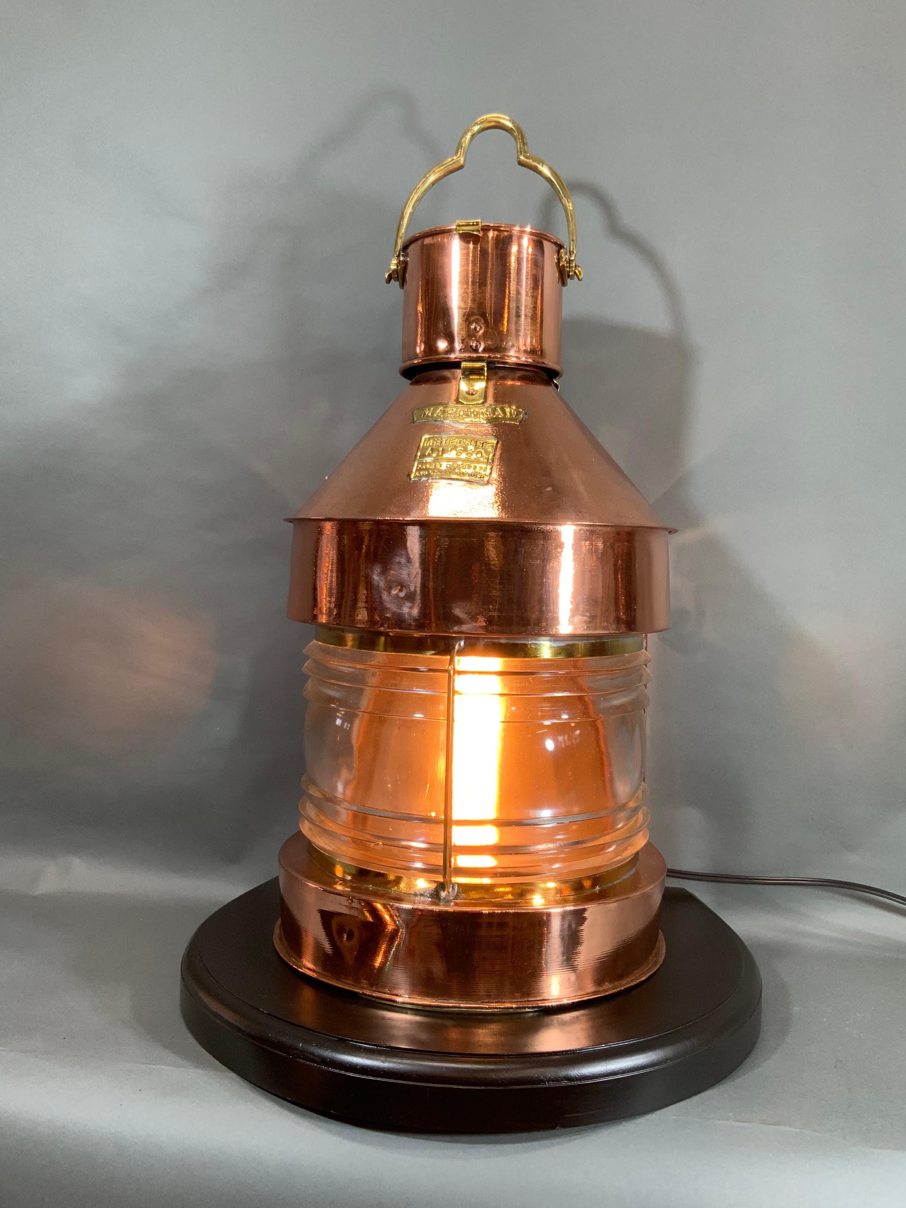 Solid copper and brass ships masthead lantern by the venerable English firm Meteorite. With brass makers badge and serial number. Interior has been fitted with an electric socket but also comes with the oil unit. Mounted to a thick mahogany base.