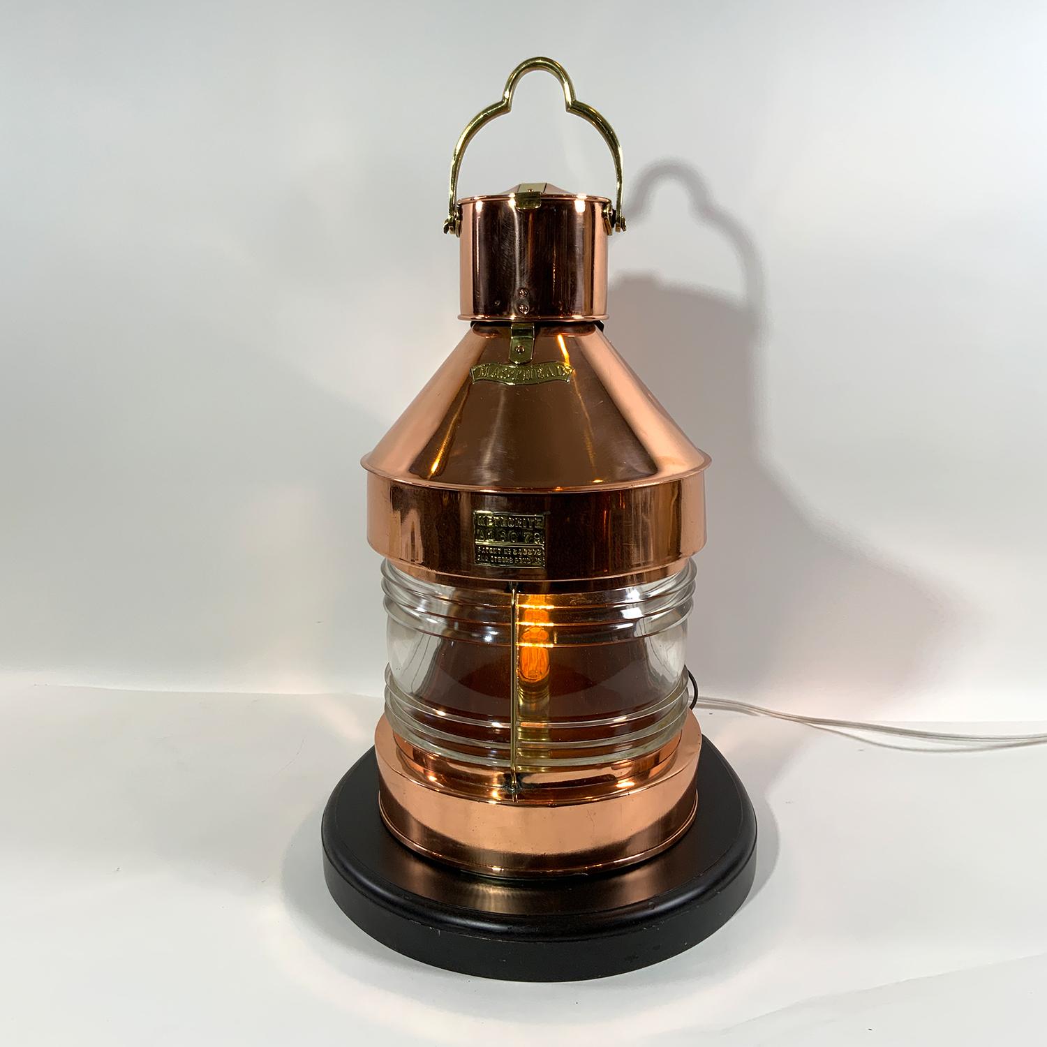 Solid copper and brass ships lantern with Fresnel glass lens. Meticulously polished and lacquered and mounted to a thick wood base. The lantern case is fitted with a makers plate from 