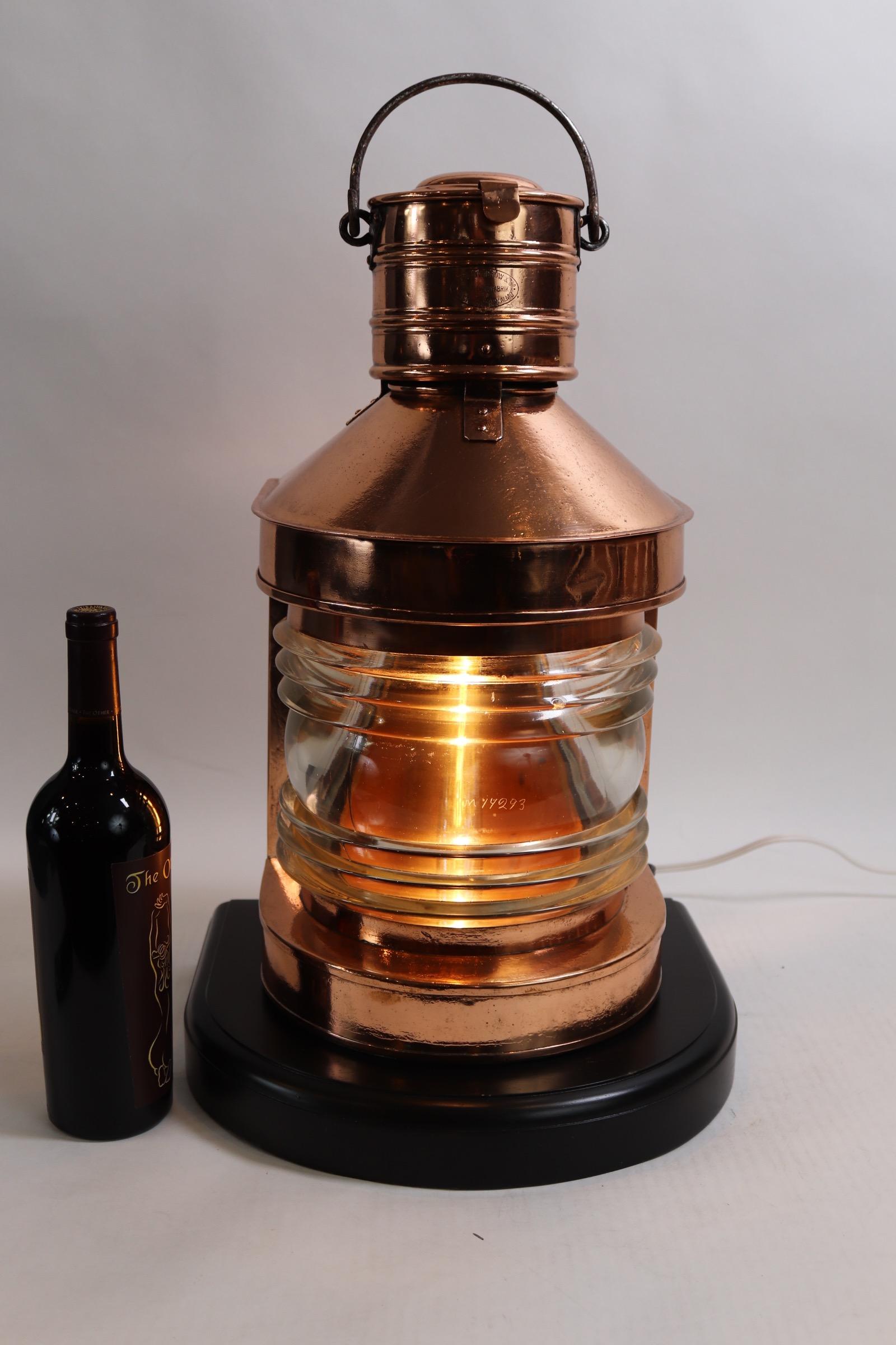 Polished copper ships masthead lantern engraved on chimney with makers name Georg Wosidkow & Co., Vastergatan Sweden. With clear glass Fresnel lens, hinged rear door, Royal hallmark on door. Lantern is mounted on a thick mahogany base with dark rich