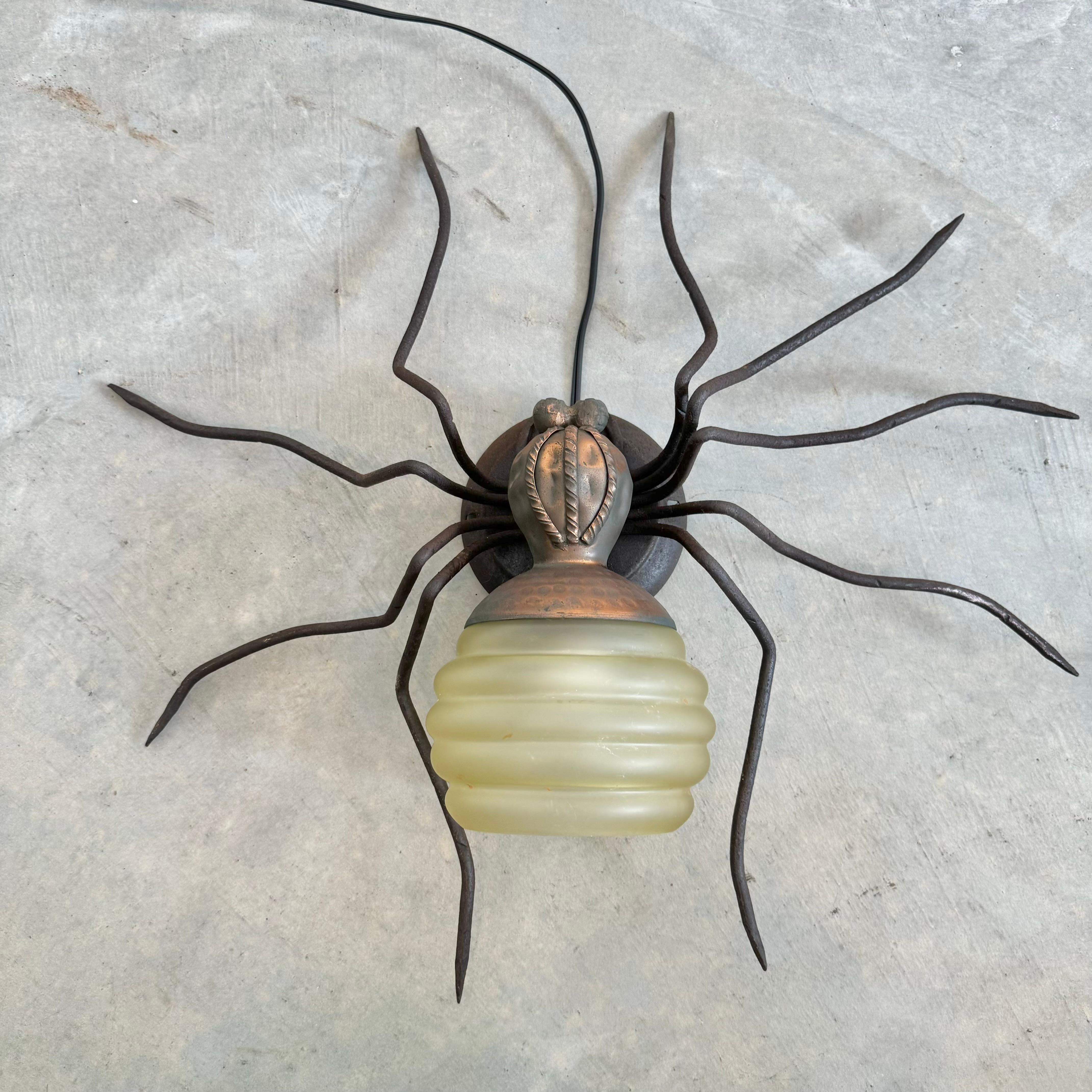 Araña única de cobre y metal hecha a mano en Italia. Gran presencia y detalle. Cuerpo de cobre martillado con cabeza negra y patas largas y esbeltas. El abdomen es un hermoso globo de cristal ámbar con un diseño anular. Este aplique tiene una base