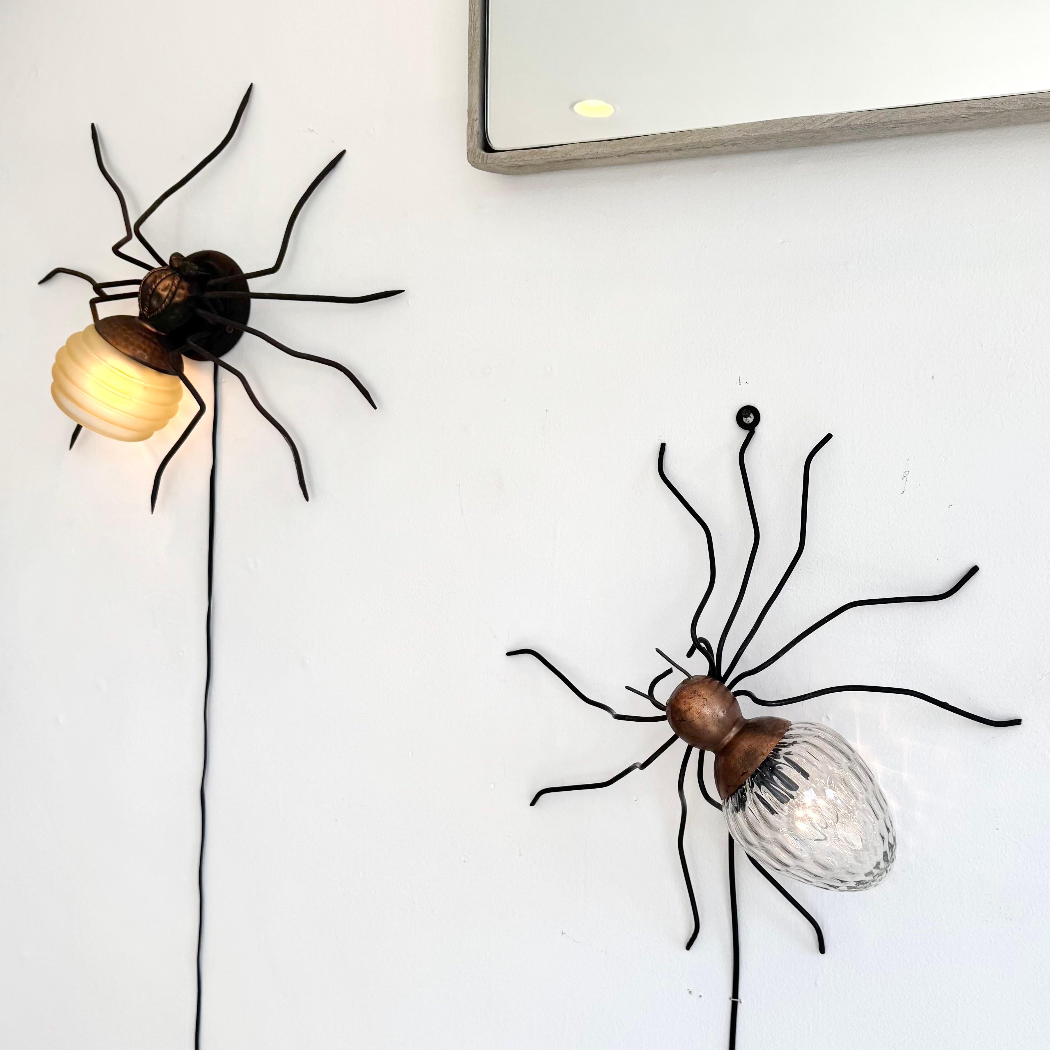 Unica applique a ragno in rame e metallo realizzata a mano in Italia. Grande presenza e dettaglio. Corpo in rame martellato con testa nera e gambe lunghe e sottili. L'addome è un bellissimo globo di vetro trasparente con una superficie piena di