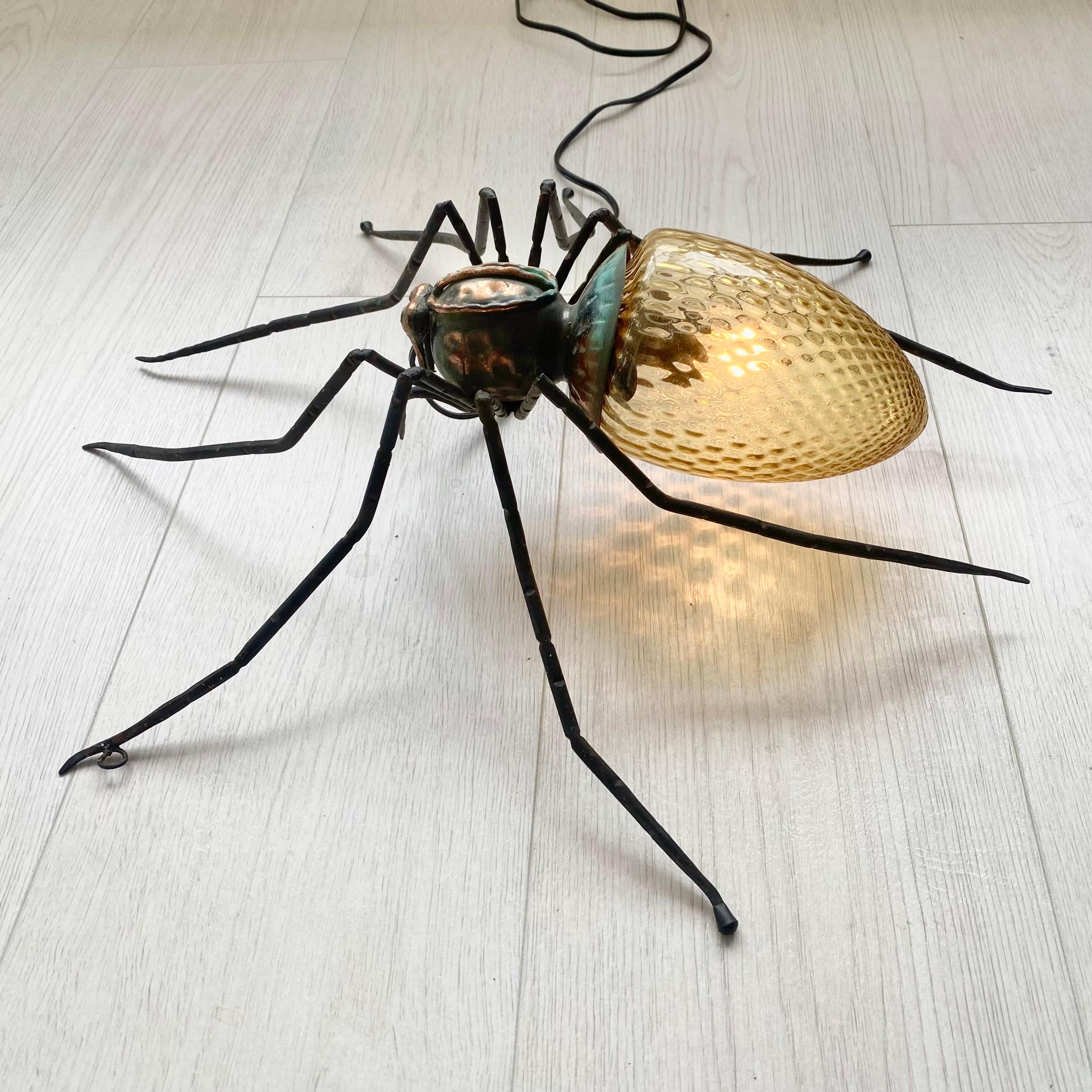 Imaginez cette araignée installée dans une pièce sombre, diffusant une chaude lueur jaune. Il s'agit d'une merveilleuse pièce de conversation et d'un éclairage d'ambiance parfait. Grande présence et détails. Corps en cuivre martelé, tête noire et