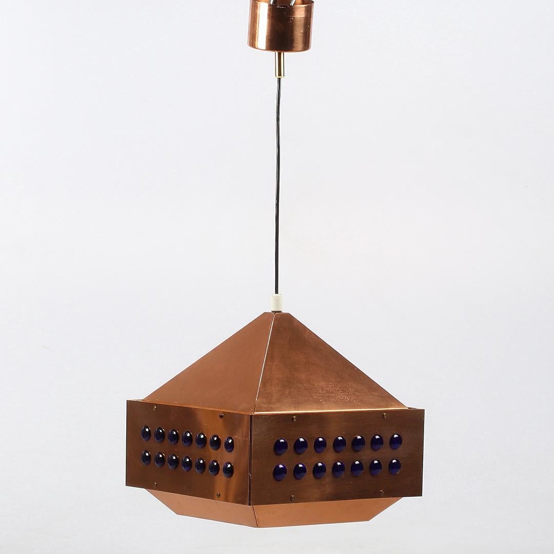 La lampe suspendue carrée en cuivre a été conçue par Hans-Agne Agnes pour Markaryd en Suède dans les années 1960. La lumière se propage de la partie en cuivre perforée en haut et de l'intérieur blanc avec des perles de verre rouges vers tous les