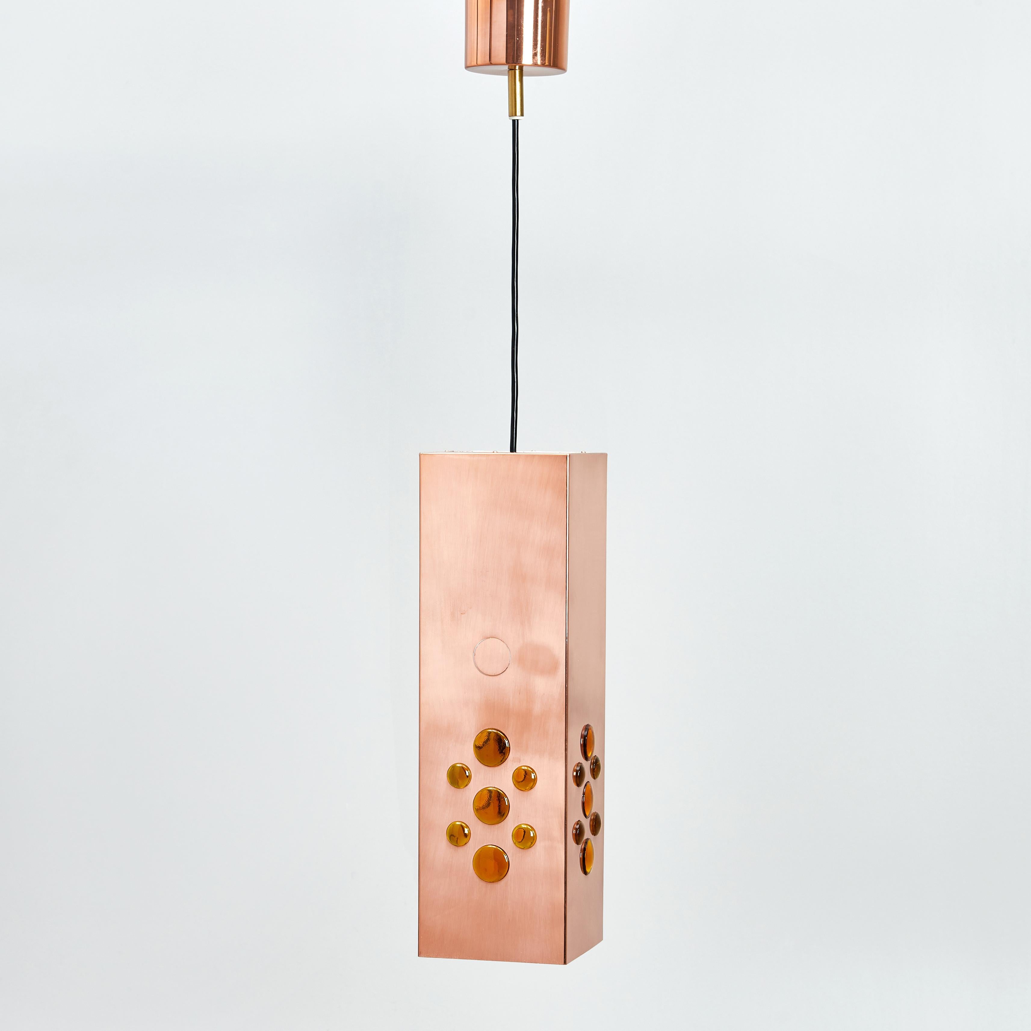 La lampe suspendue carrée en cuivre a été conçue par Hans-Agne Agnes pour Markaryd en Suède dans les années 1960. La lumière se propage de la partie perforée en cuivre en haut et de l'intérieur blanc avec des perles de verre orange vers tous les