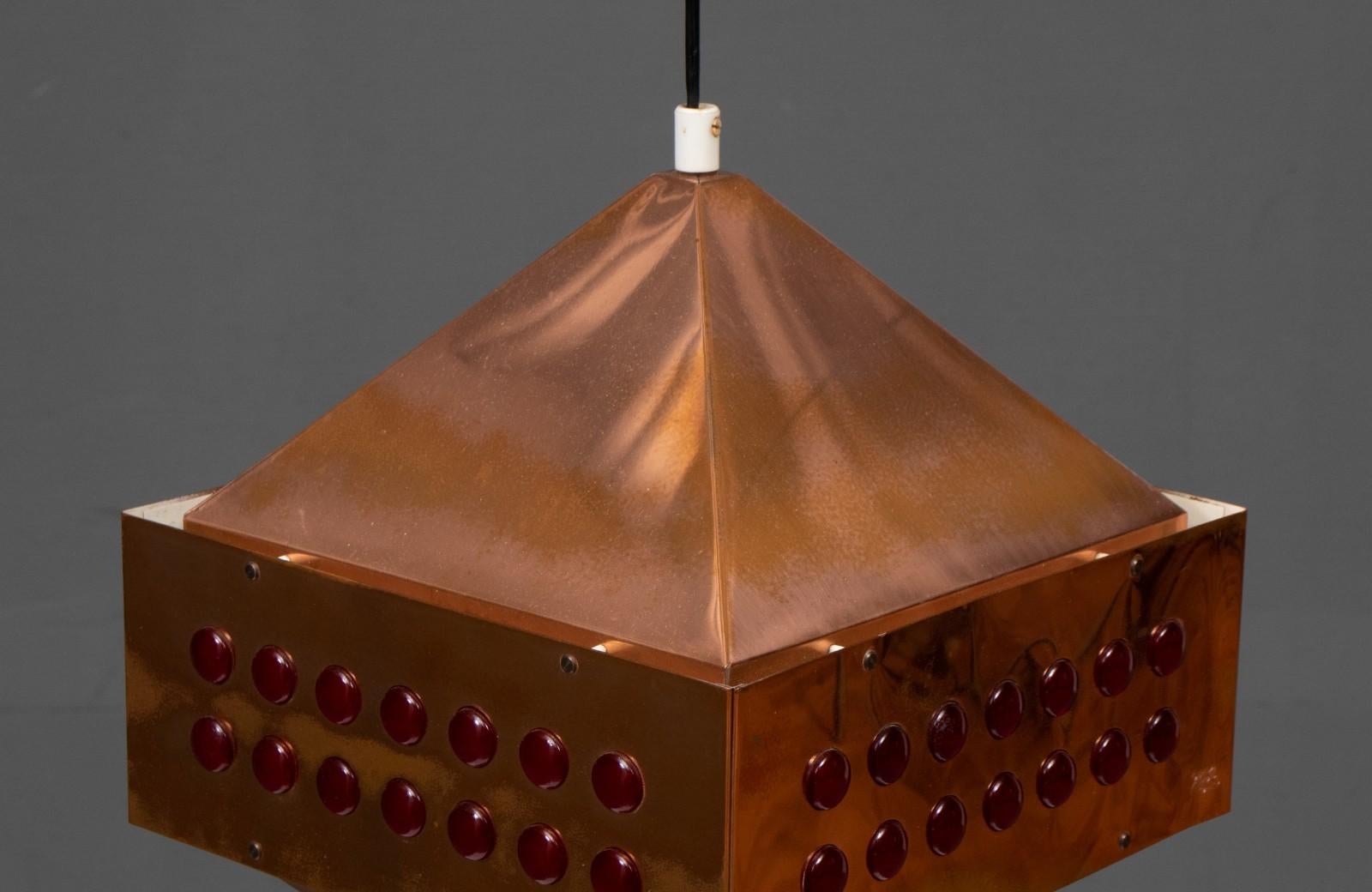 Square copper pendant lamp was designed by Hans-Agne Jakobsson for Markaryd in Sweden in the 1960s. The light spreads from the perforated copper part at the top and the white inside with red glass beads to all sides below. All are original and in