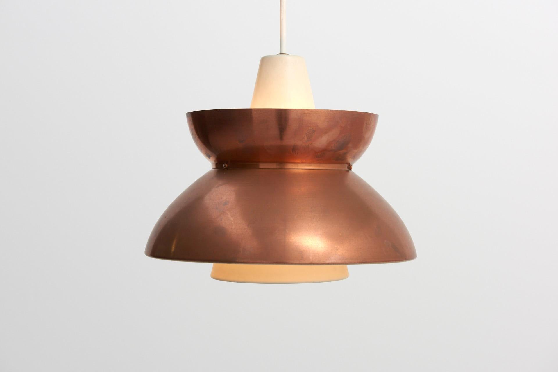 A pendant ceiling lamp designed by architect Jørn Utzon for the Navy Buildings department, 'Søværnspendel'. Patinated copper on the outside and white lacquered metal on the inside. Made in Denmark by Louis Poulsen.