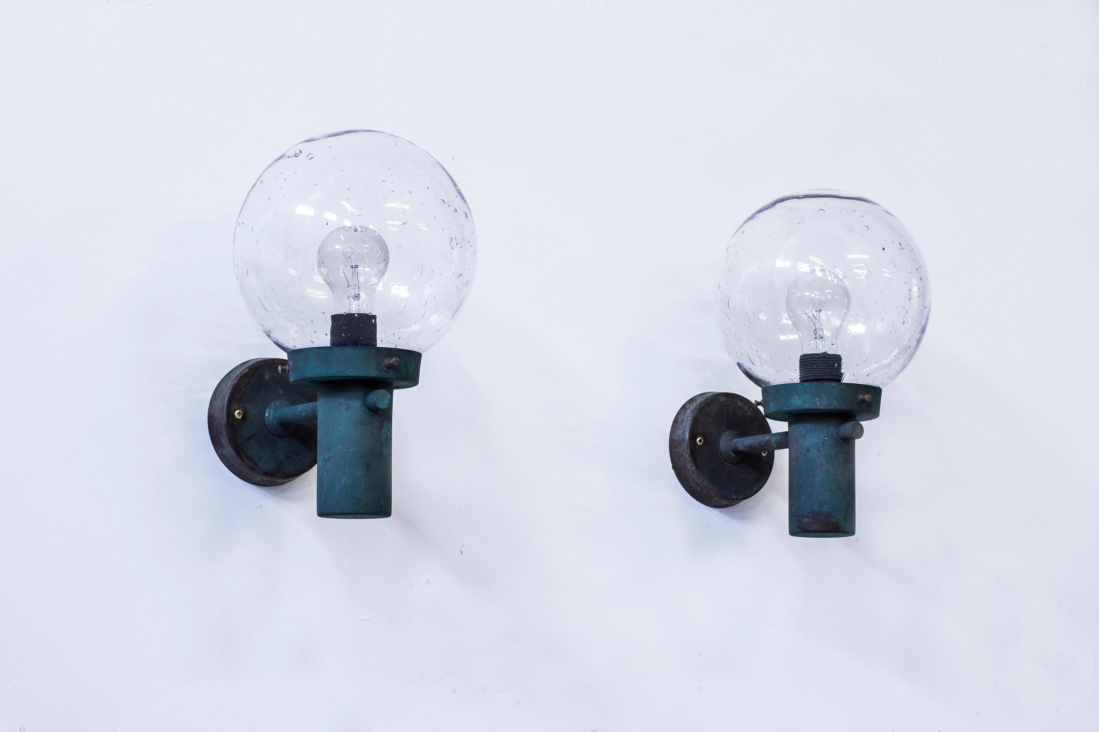 Wall lamps designed by Anders Pehrson. Produced by Ateljé Lyktan in the 1960s. Made from solid copper with hand blown clear glass shades. Very good condition with original patina to the copper.
 
