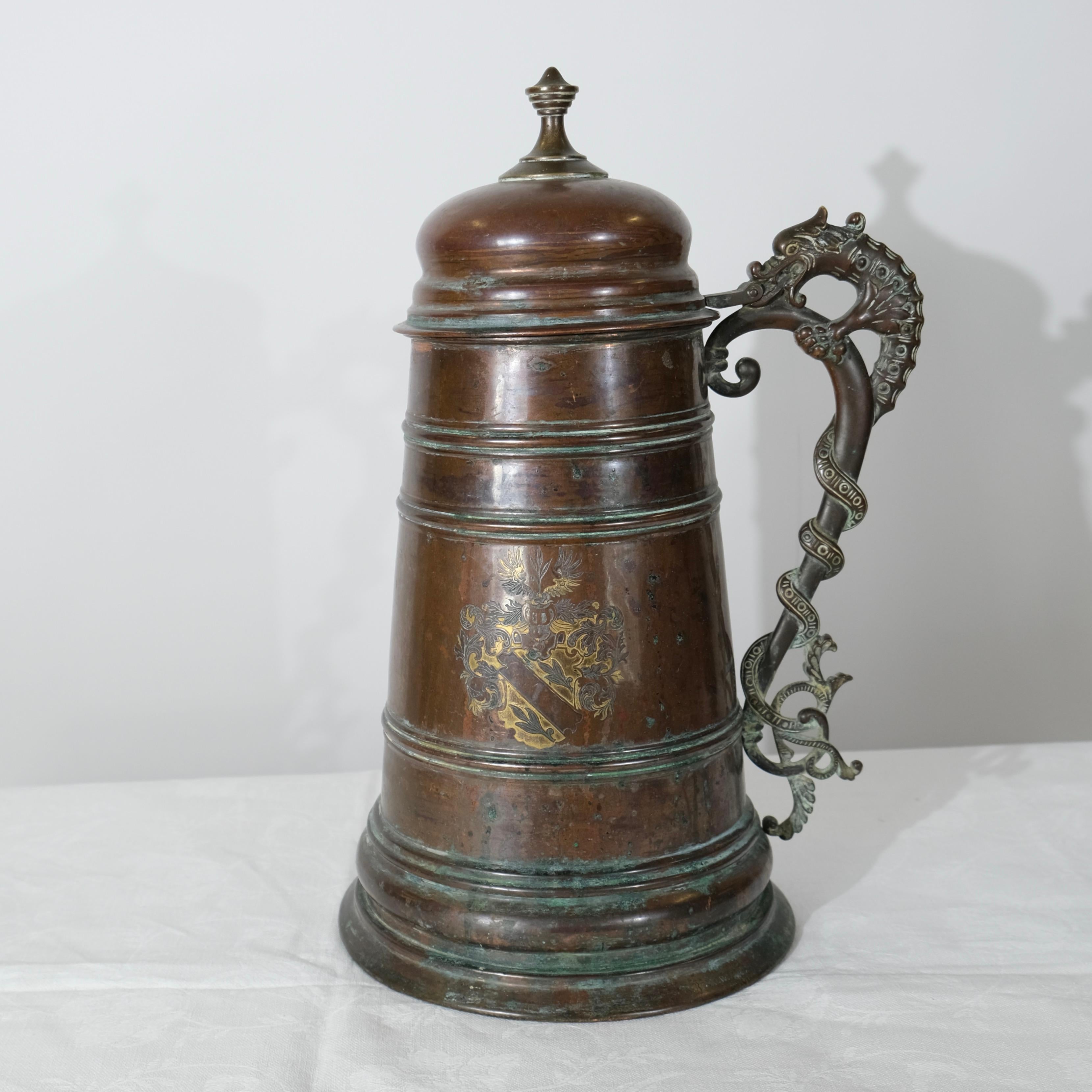 Questa brocca di rame, realizzata da B. Beskow nel 1908 a Eskilstuna, in Svezia, è un notevole esempio di antico design nordico vichingo. La brocca presenta una forma cilindrica robusta e affusolata con bande orizzontali che ne accentuano la