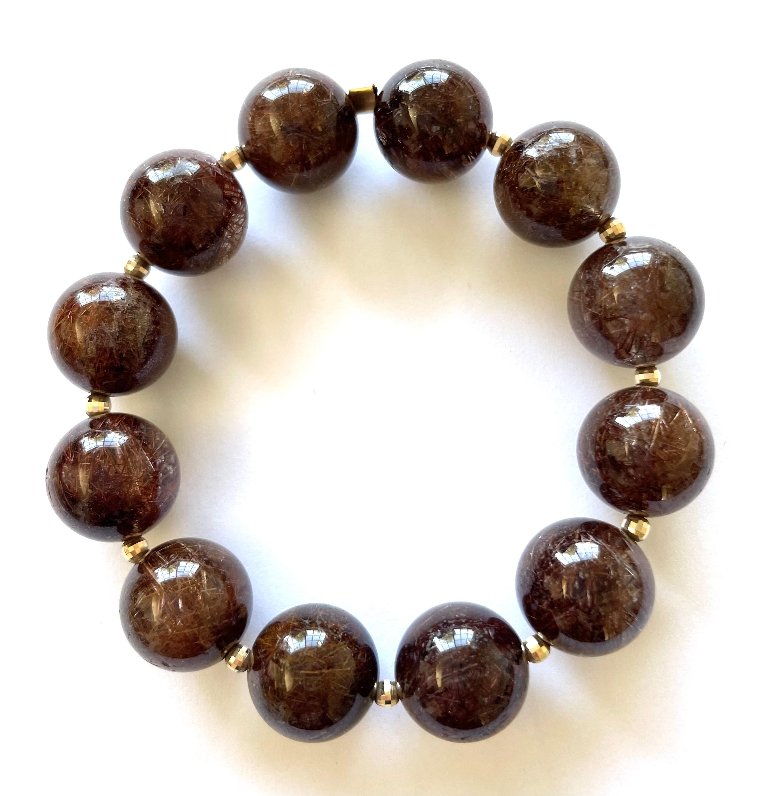 Description
Superior quality coppery-brown Rutilated Quartz stretchy bracelet, accented with 14k yellow gold faceted balls.
Item # B1253

Materials and Weight
Rutilated Quartz, 15mm, 250 carats.
3mm faceted balls, 14k yellow gold. 

Dimension 
Size