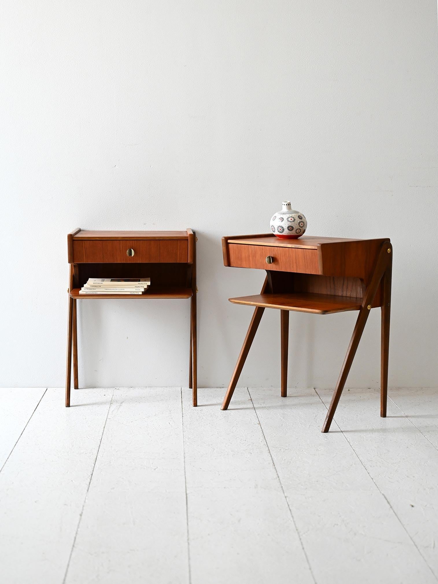 Coppia di comodini vintage anni '50 con cassetto e maniglia in ottone scolpito, dotati di mensola inferiore.

Coppia di comodini scandinavi originali degli anni ’50 in legno di teak, dal design elegante e ricercato. Ogni pezzo è dotato di un