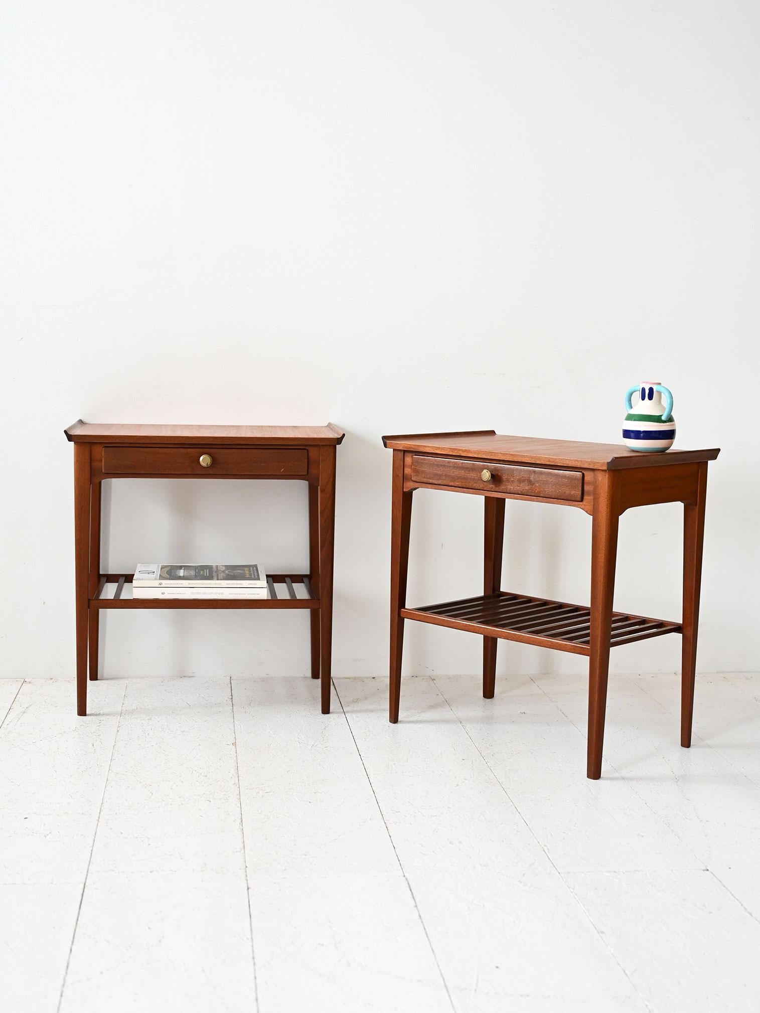 Coppia di comodini in mogano con cassetto e mensola a listelli, produzione scandinava metà Novecento.

Coppia di comodini scandinavi vintage realizzati in mogano, databili alla metà del Novecento. Ogni comodino è dotato di un cassetto con pomello in