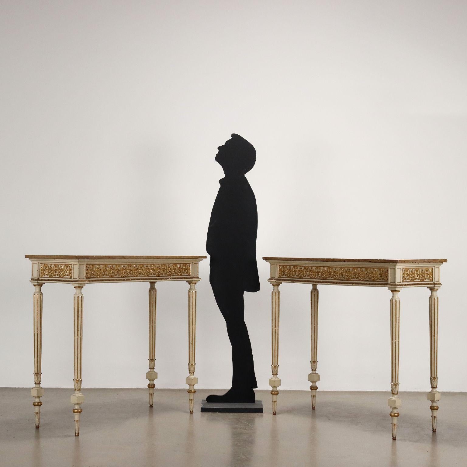 Coppia di consolle in stile neoclassico inizi '900. Quattro gambe tronco coniche tornite  e intagliate reggono un piano in marmo poggiante su fascia intagliata coi tipici motivi a palmette e antemi, gli intagli sono dorati a guazzo su un fondo