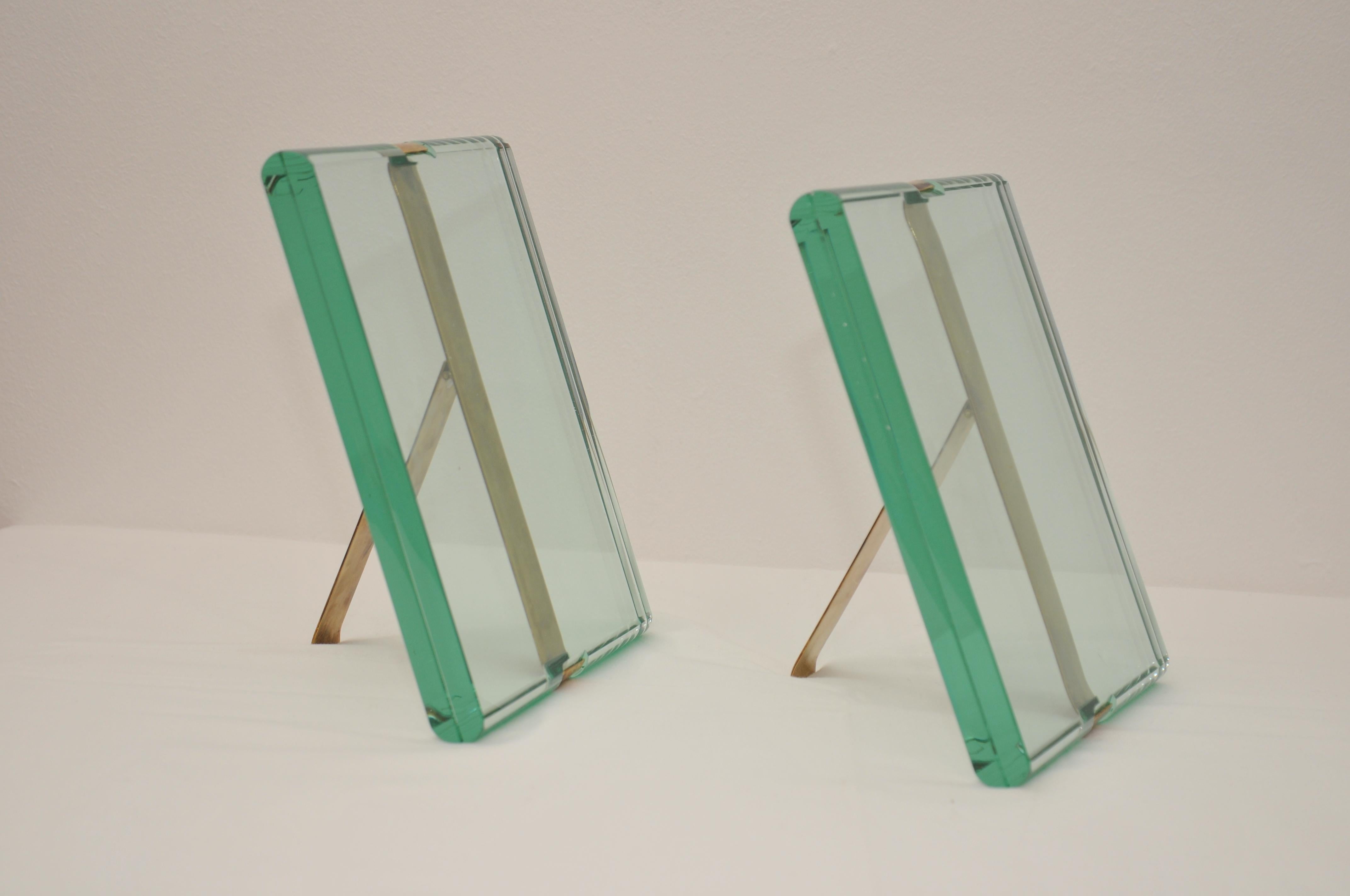Eleganza senza tempo racchiusa in un set di cornici portafoto disegnate da Max Ingrand per Fontana arte. mod 1370\1 composto da una fascia in ottone, che nella sua curvatura mantiene incastonati i due cristalli tagliati a mano, creando un intenso