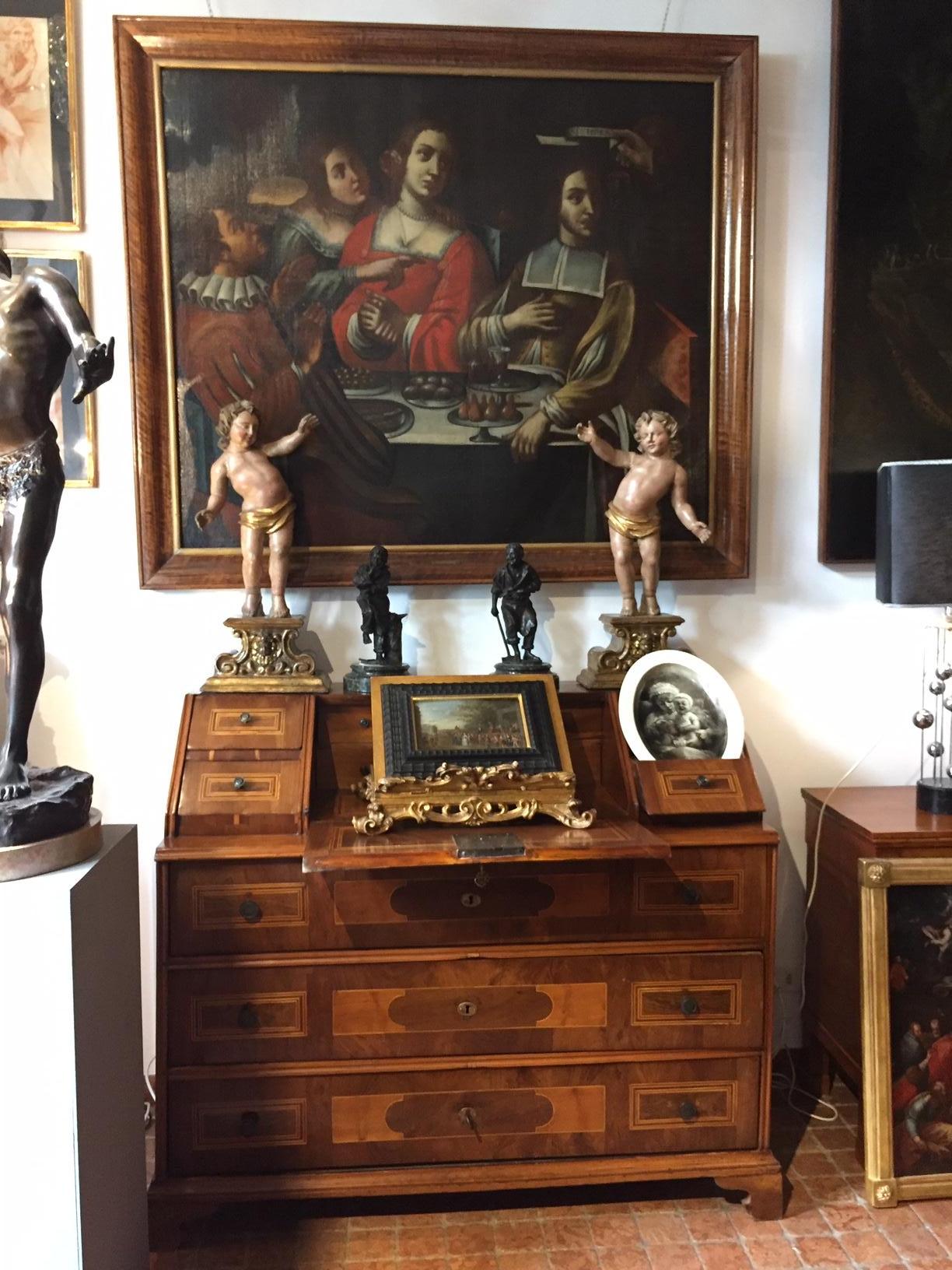 Coppia di Putti in Legno Intagliato su Base Scolpita del 1700 sono due cherubini nudi coperti solamente dal perizoma dorato; apparentemente due angeli annuncianti senza le ali, sono eretti in punta dei piedi con una postura sinuosa e con le braccia