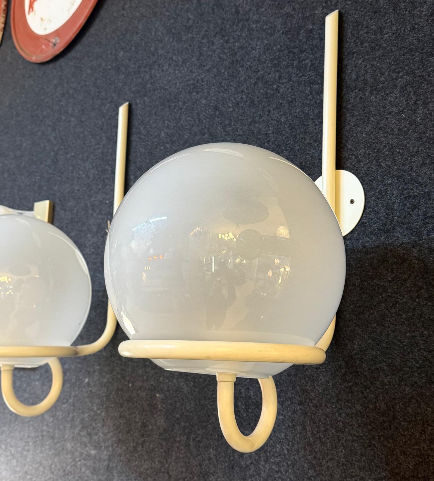 Splendida coppia di applique vintage disegnate da Sergio Asti negli anni '70 che incarna l’eleganza senza tempo e la ricerca stilistica tipica del grande designer italiano. Perfette per ambienti dal gusto raffinato, queste lampade da parete uniscono