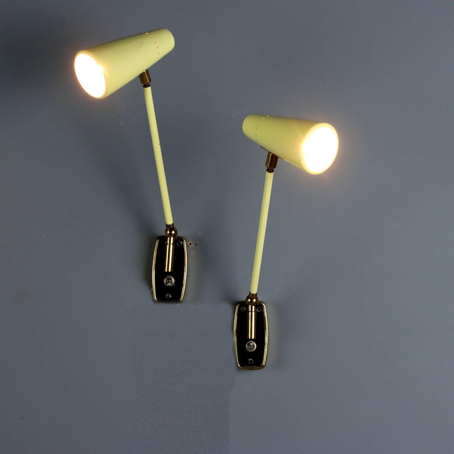 Deux lampes murales vintage de la fin des années 1950 de la production Stilnovo, ajustables et faites de métal laqué jaune avec des joints en laiton. La marque du fabricant est gravée au dos.