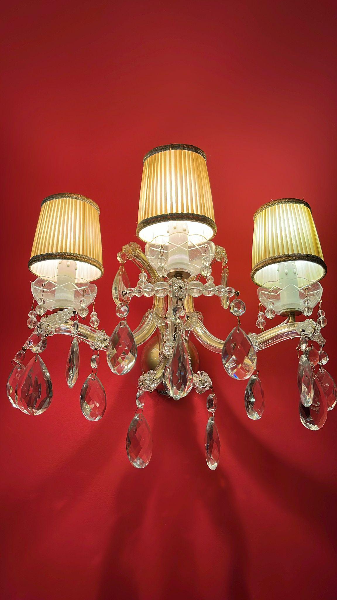Pair Of Italian Crystal Appliquesa three-light, mid-20th century Maria Theresa style, with  three curved arms and three  e14 lights, for a maximum capacity of 180 watts, in good condition, ready to hang. The gilded iron structure is  entirely