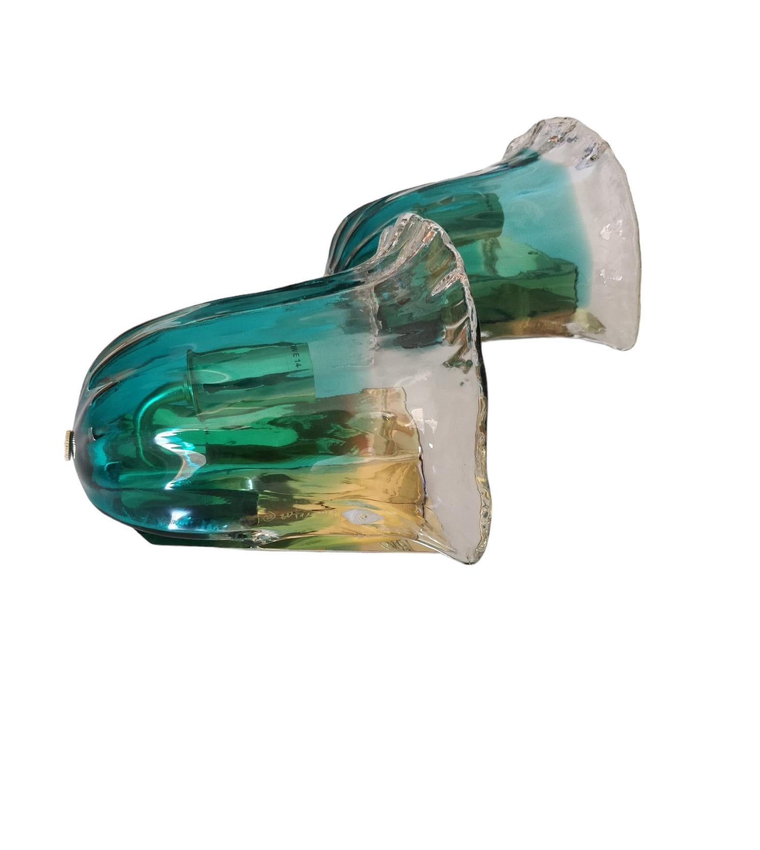 
Il vetro, modellato a forma di fiore, unisce armoniosamente tonalità verdi e trasparenti, creando un effetto visivo di grande fascino quando la luce si accende. Il bagliore verde diffonde un'atmosfera calda e avvolgente, mentre la parte superiore