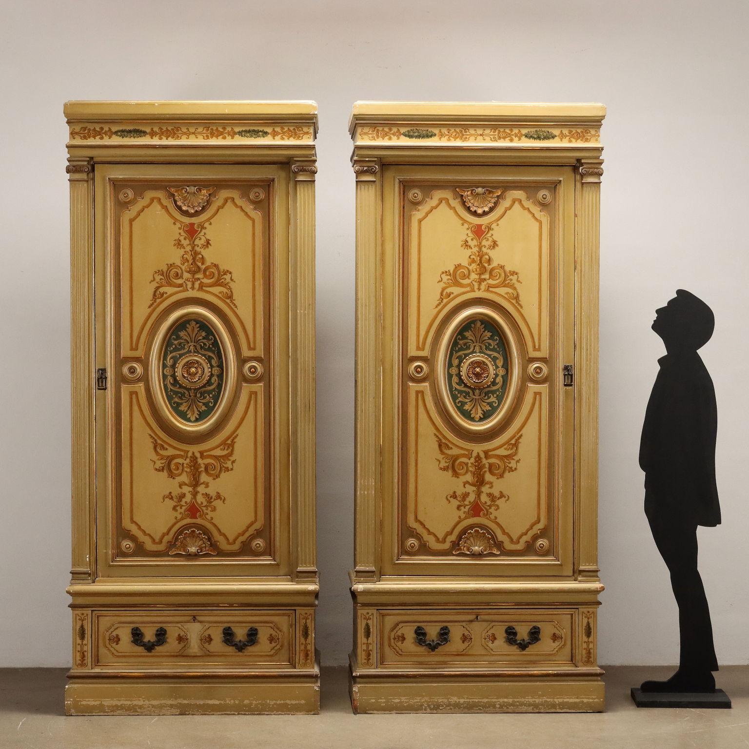 Pair of style closets with door and drawer in the lower band, Italy 20th century. Entirely lacquered, they are adorned with gilded carvings and painted with festoon motifs, curls and phytomorphic elements. Embellished with gold moldings. The sashes