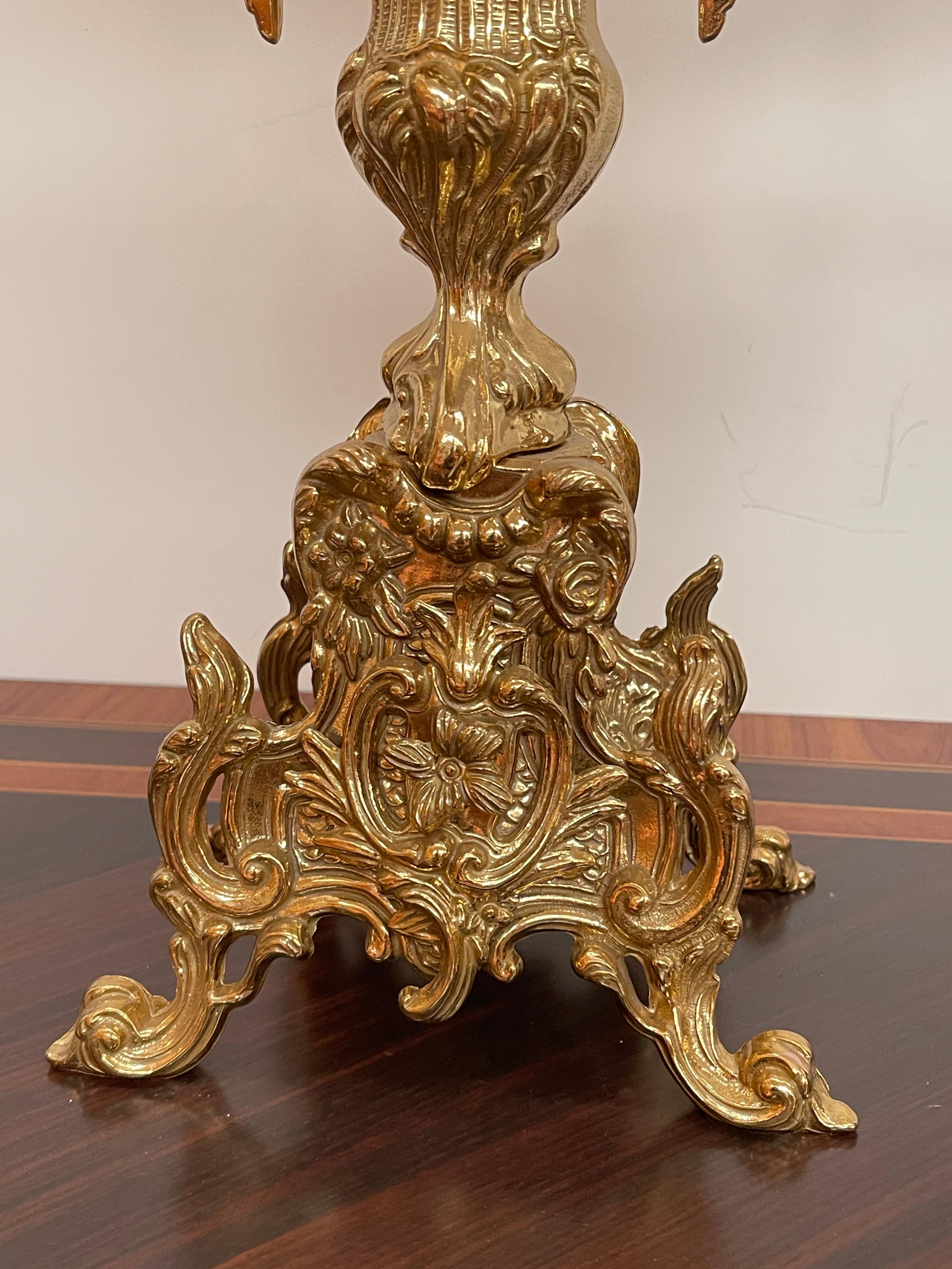 Magnifica coppia di candelabri a cinque fiamme in pregiato bronzo dorato, finemente lavorati nello sfarzoso stile Rococò francese del XIX secolo. Ogni candelabro presenta ricchi dettagli ornamentali con motivi fogliati, volute e decori floreali,