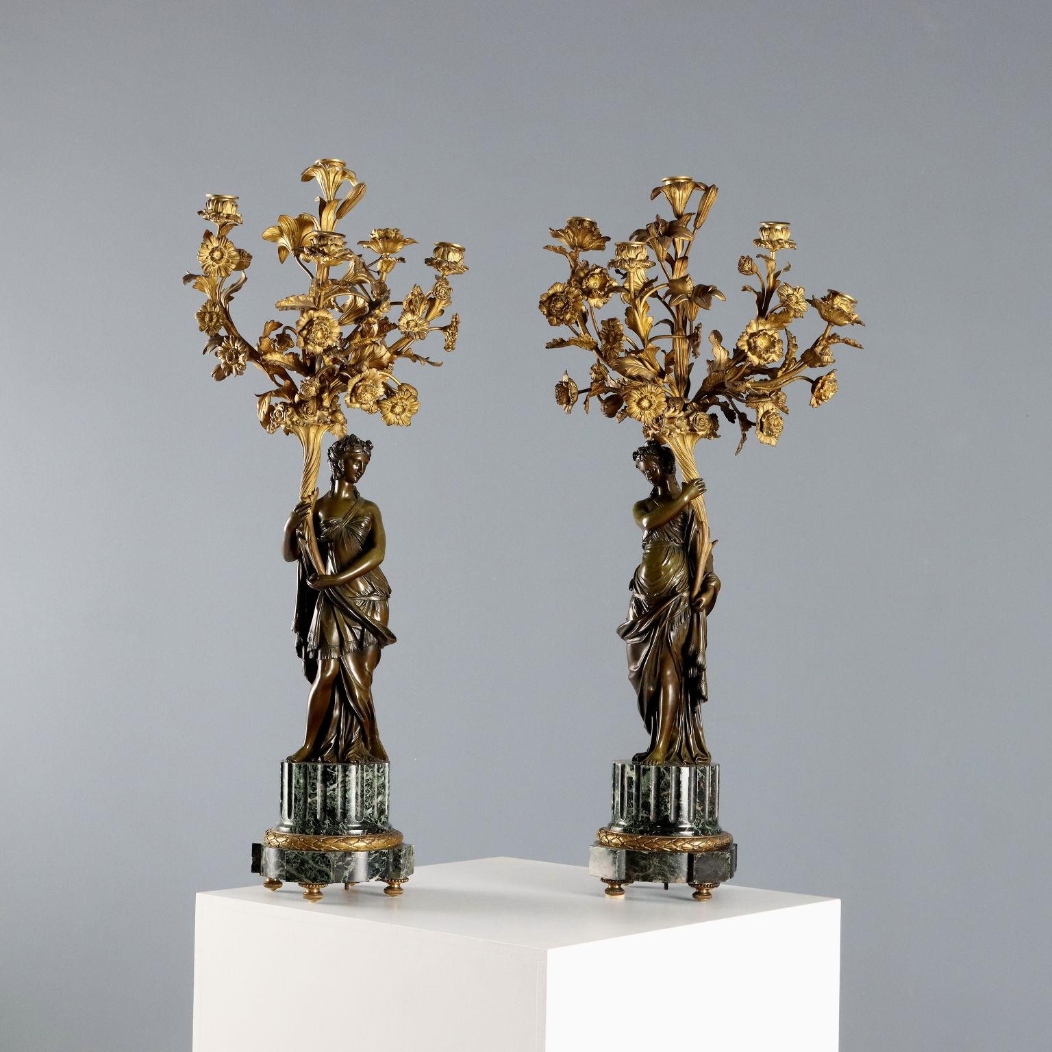 Pair of bronze candelabra with five arms in the shape of flowering branches held up by female figure with cornucopia. Green Alpi marble base with fluted column section with feet and chiseled bronze serum. 