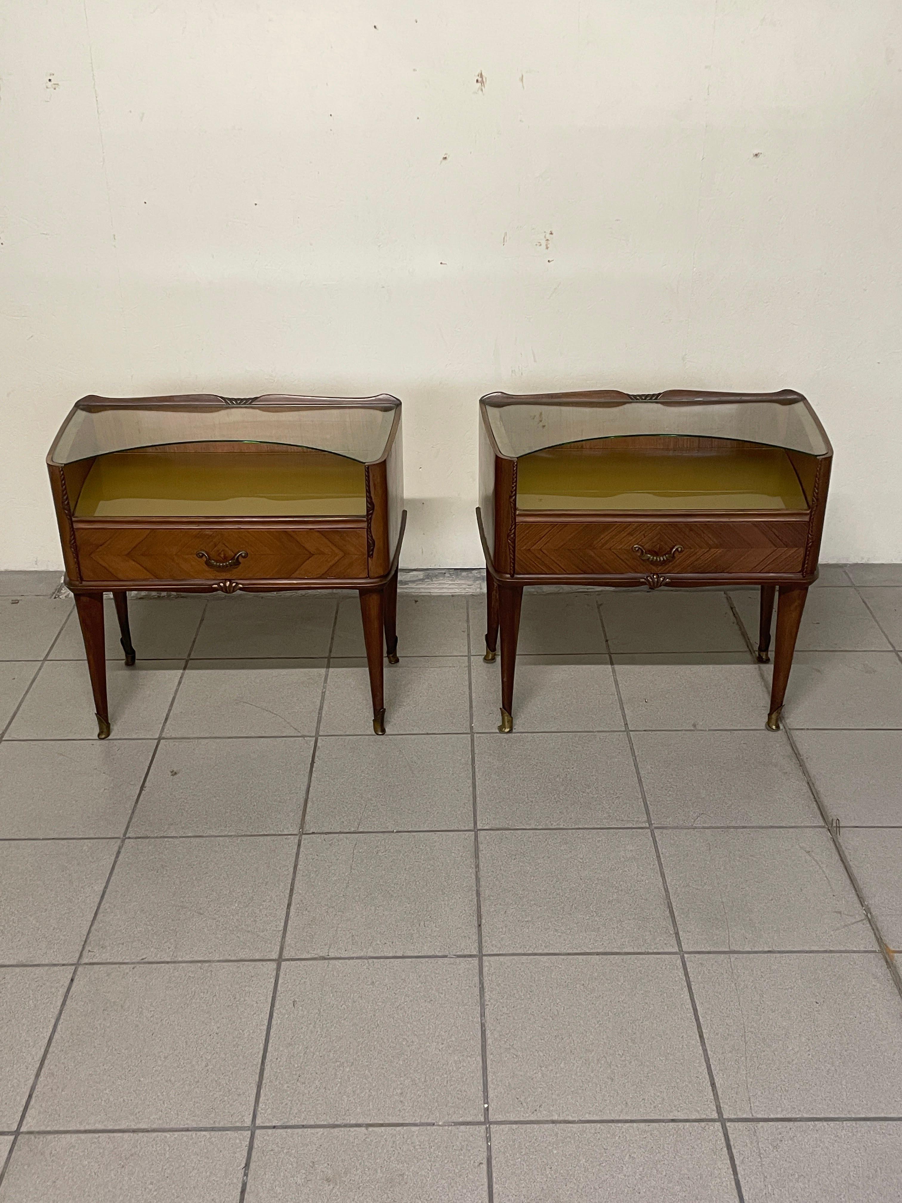 Paire de tables de chevet des années 1950 en bois de rose, plateau en verre doré et étagère en verre façonné.

Détails et bagues en laiton. 

Ils sont en bon état, un repolissage devrait être envisagé pour donner encore plus de corps au bois