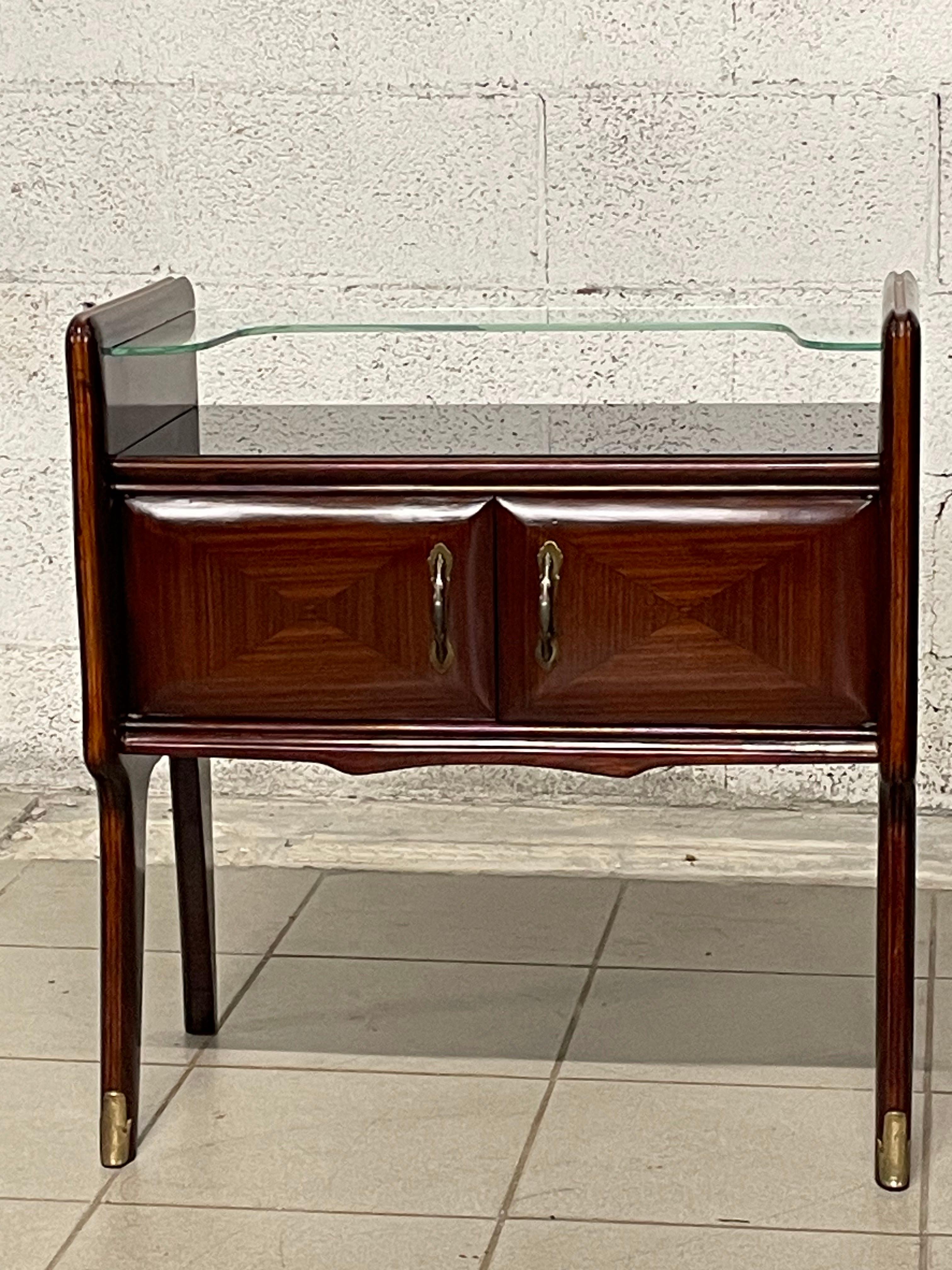 Pair of elegant nightstands from the 1950s fully restored.

Mahogany wood frame with black glass top and clear glass shaped shelf.

Brass details lend elegance and style to this pair of nightstands.
